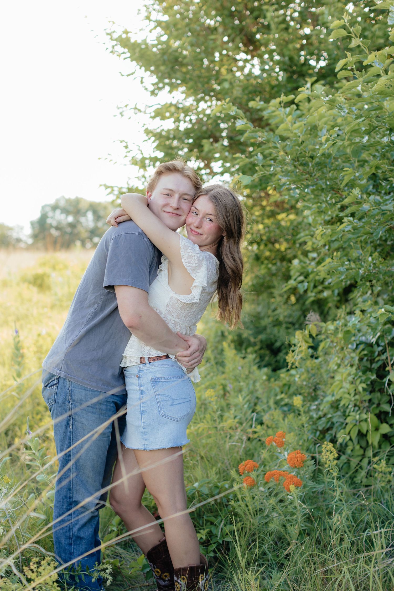 Romantic photo of a couple embracing on a hilltop at Prairie Bluffs, surrounded by open fields and wide Minnesota skies.