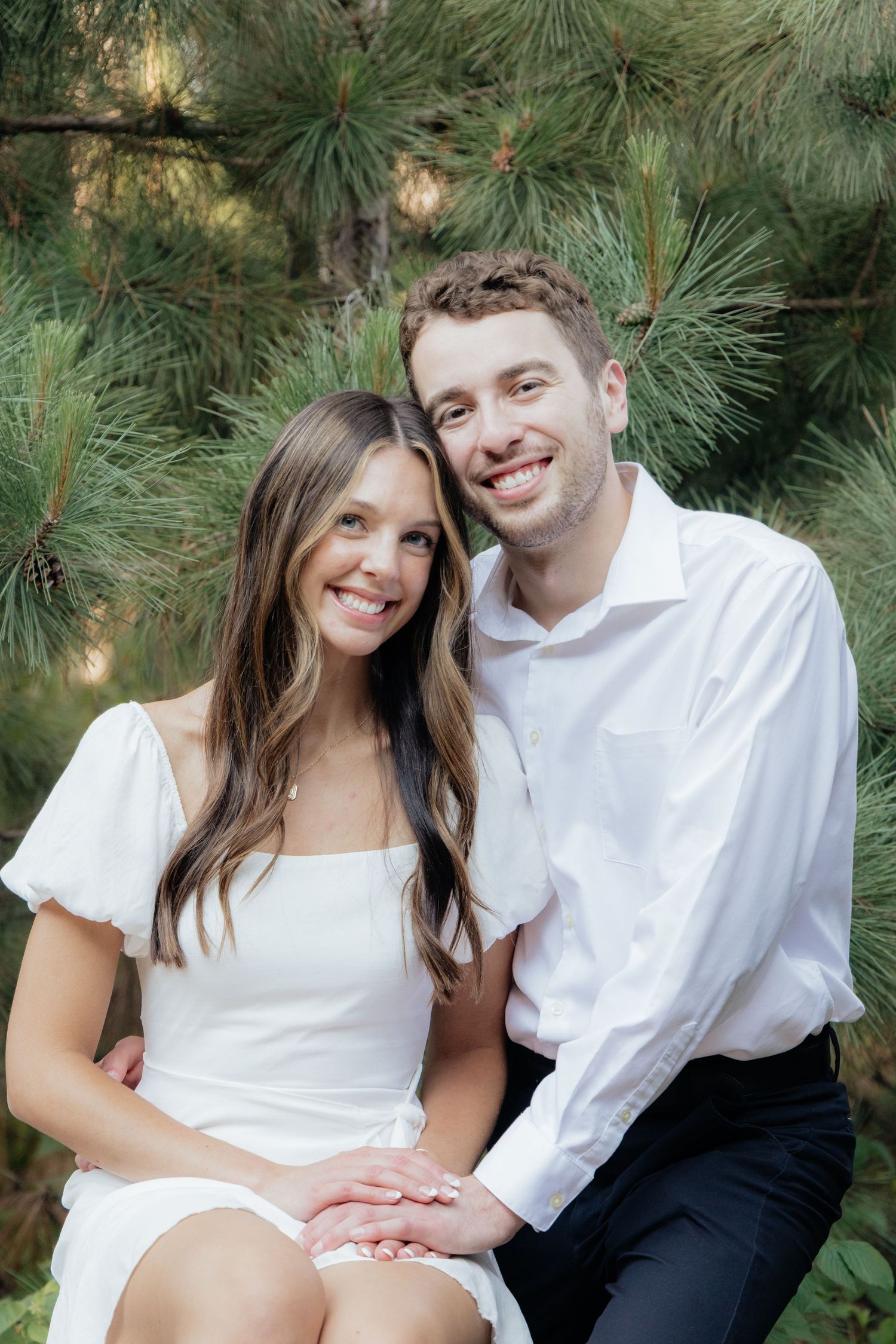 Golden-hour portrait of a couple embracing among tall trees at Pinewood in Cambridge, showcasing woodsy elegance.