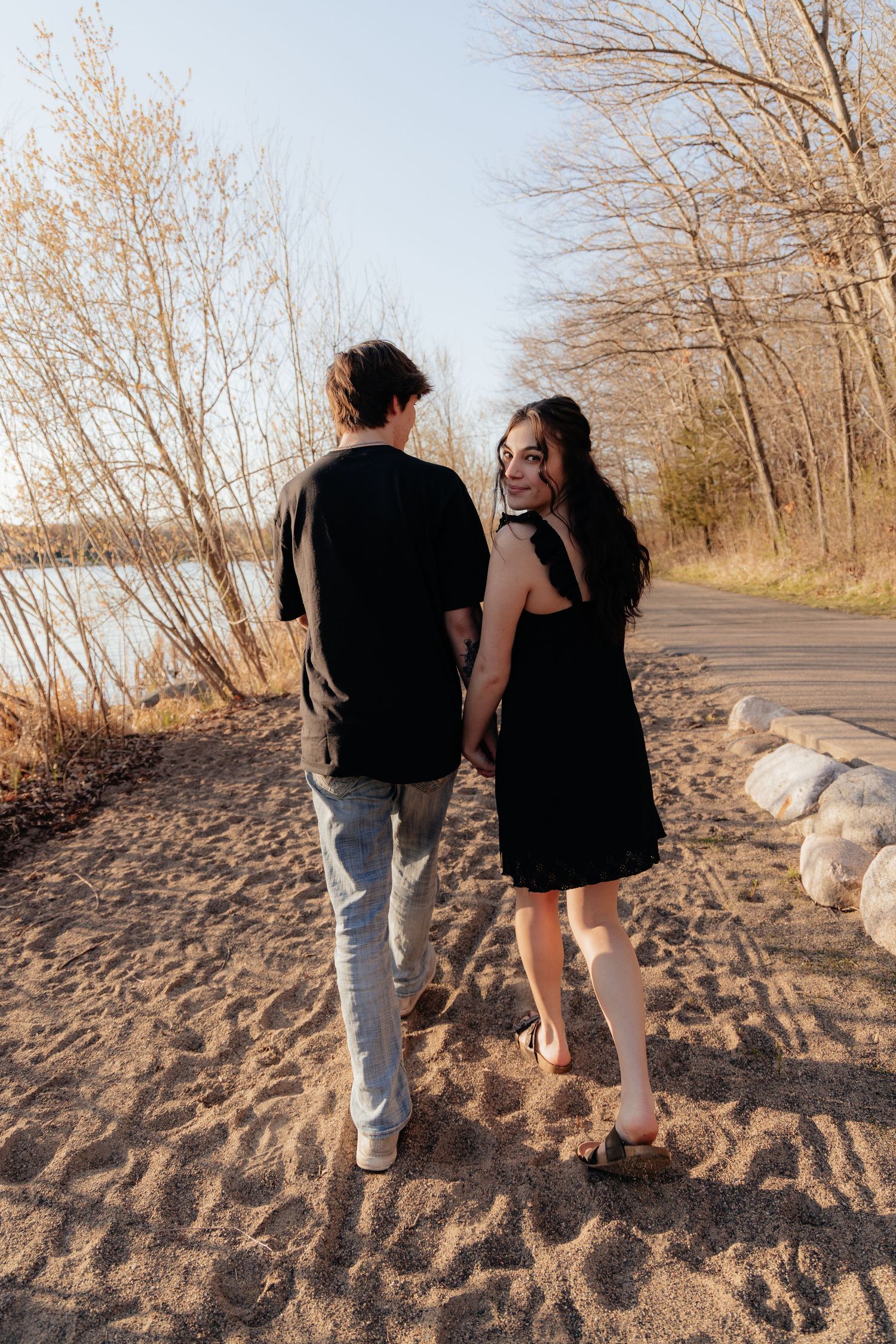 Couple laughing enjoying the blooming trees at Fish Lake Regional Park in Maple Grove, MN, with fresh green grass and soft spring sunlight