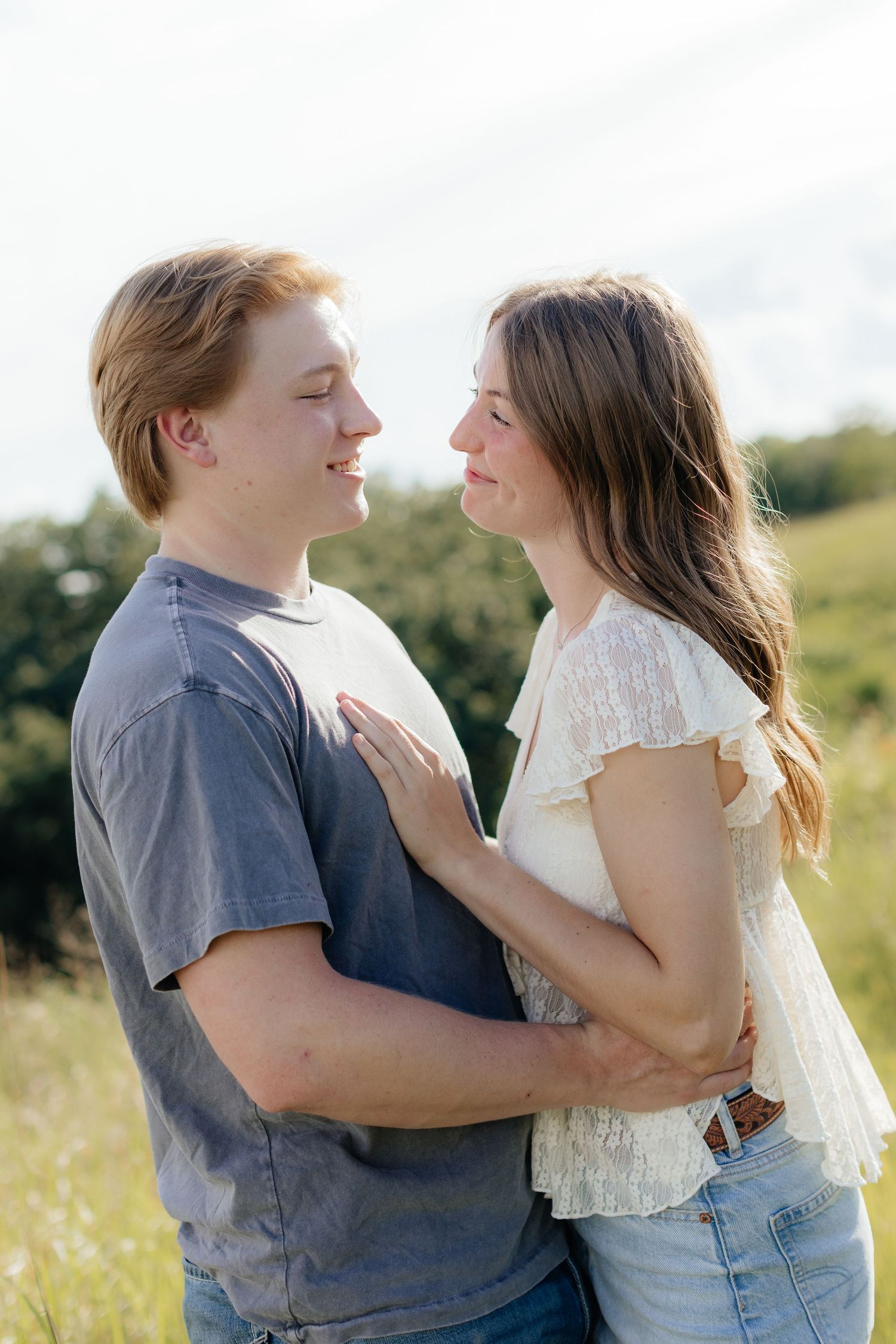 Romantic photo of a couple embracing on a hilltop at Prairie Bluffs, surrounded by open fields and wide Minnesota skies.