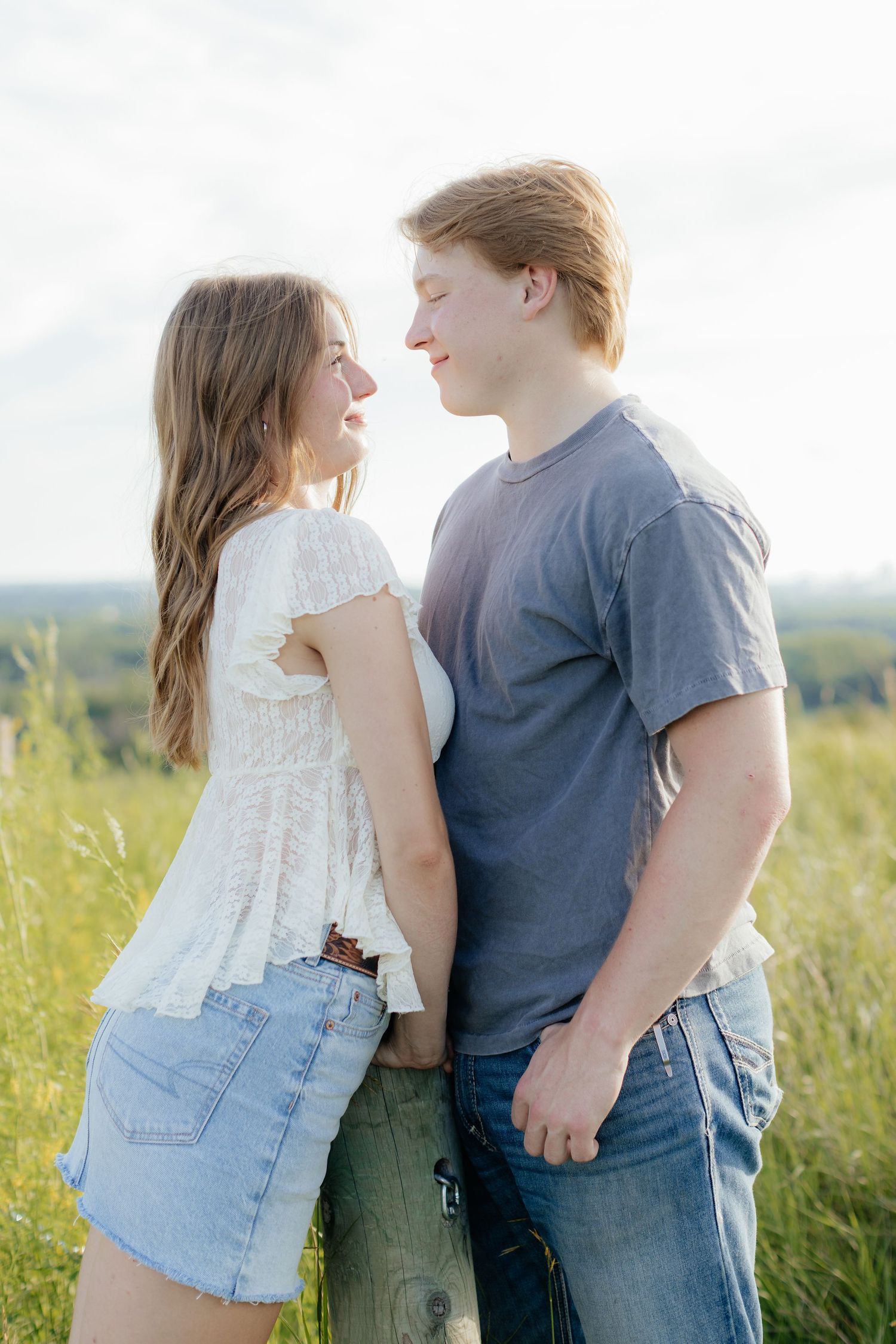 Romantic photo of a couple embracing on a hilltop at Prairie Bluffs, surrounded by open fields and wide Minnesota skies.