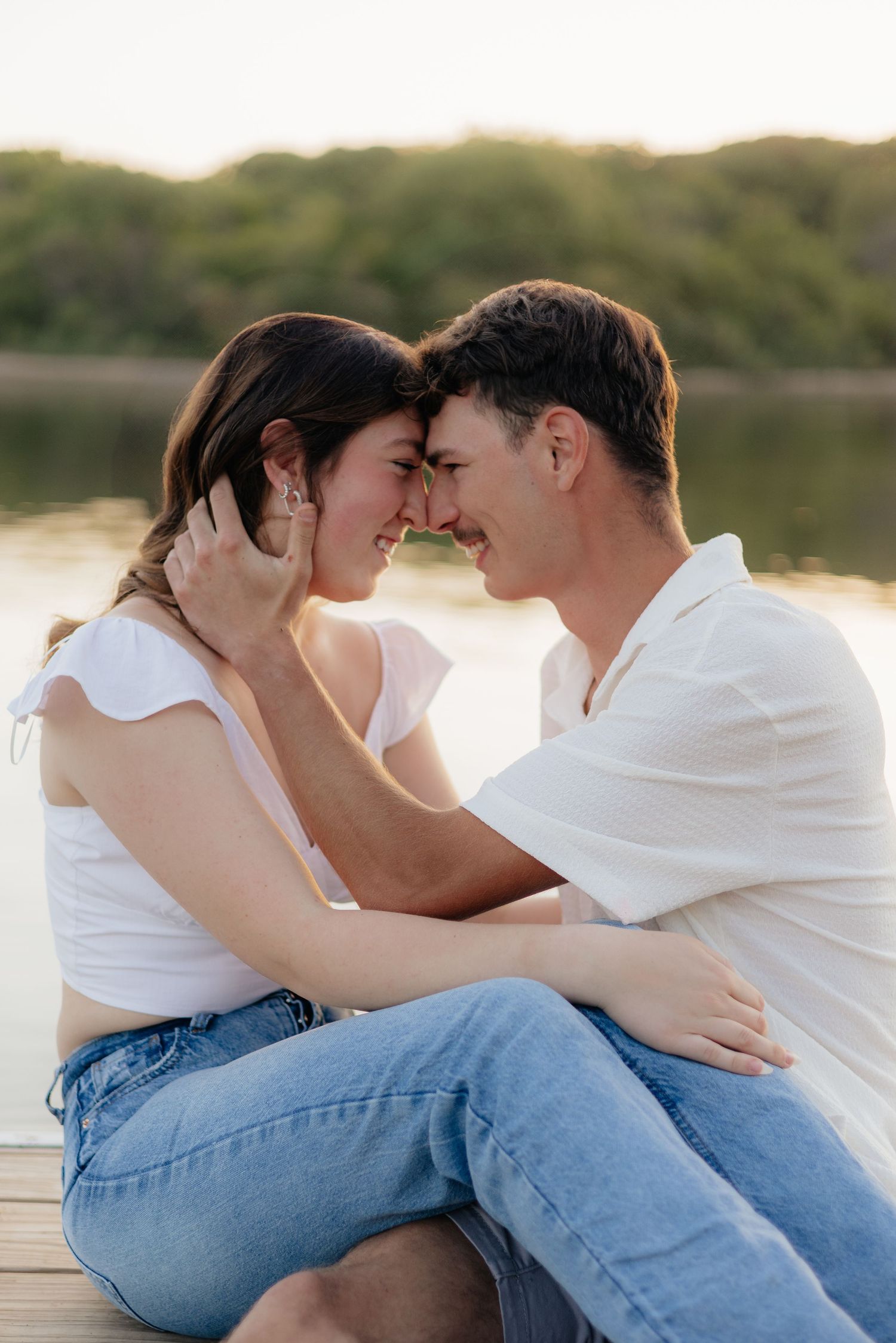Couple smiling together along the lakeshore at Fish Lake Regional Park in Maple Grove, MN, with bright green trees and clear blue water