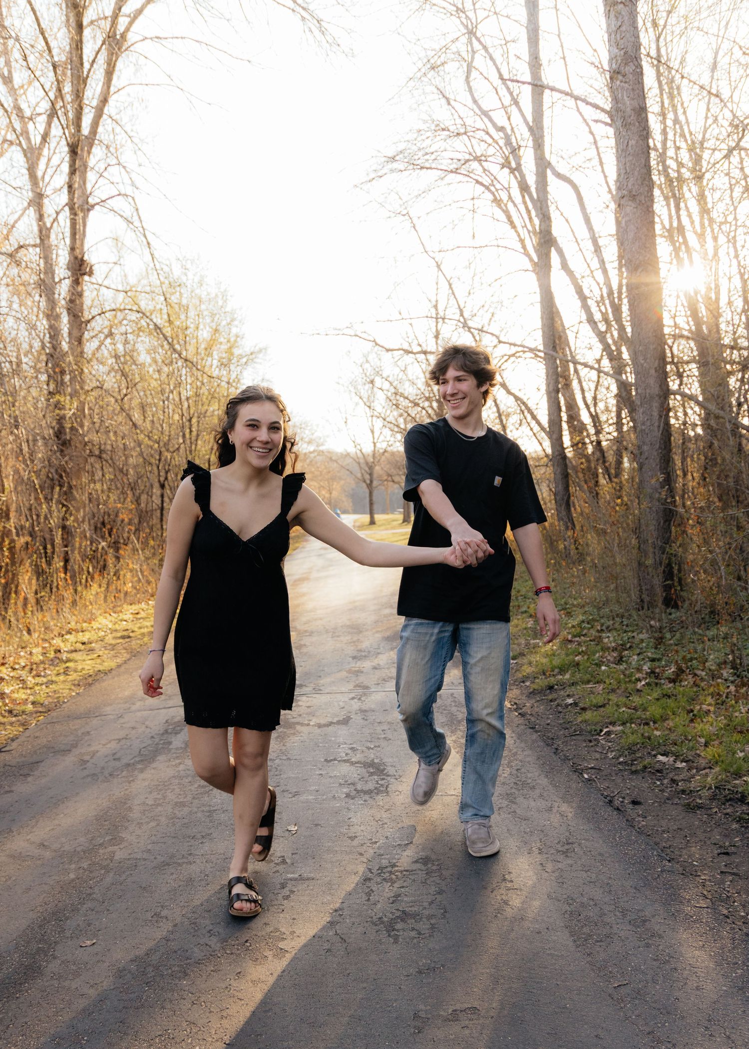 Couple laughing enjoying the blooming trees at Fish Lake Regional Park in Maple Grove, MN, with fresh green grass and soft spring sunlight