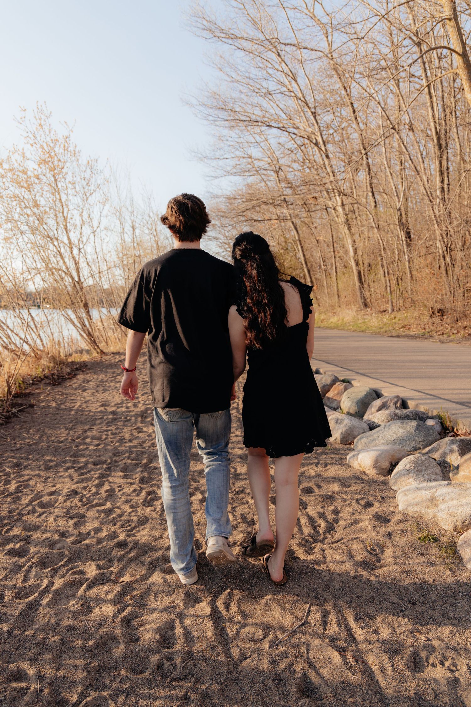 Couple laughing enjoying the blooming trees at Fish Lake Regional Park in Maple Grove, MN, with fresh green grass and soft spring sunlight