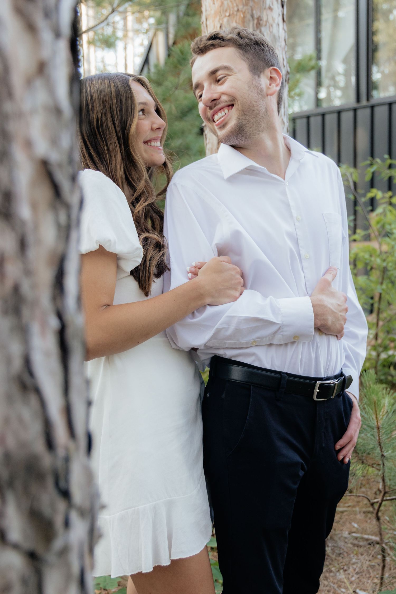 Golden-hour portrait of a couple embracing among tall trees at Pinewood in Cambridge, showcasing woodsy elegance.