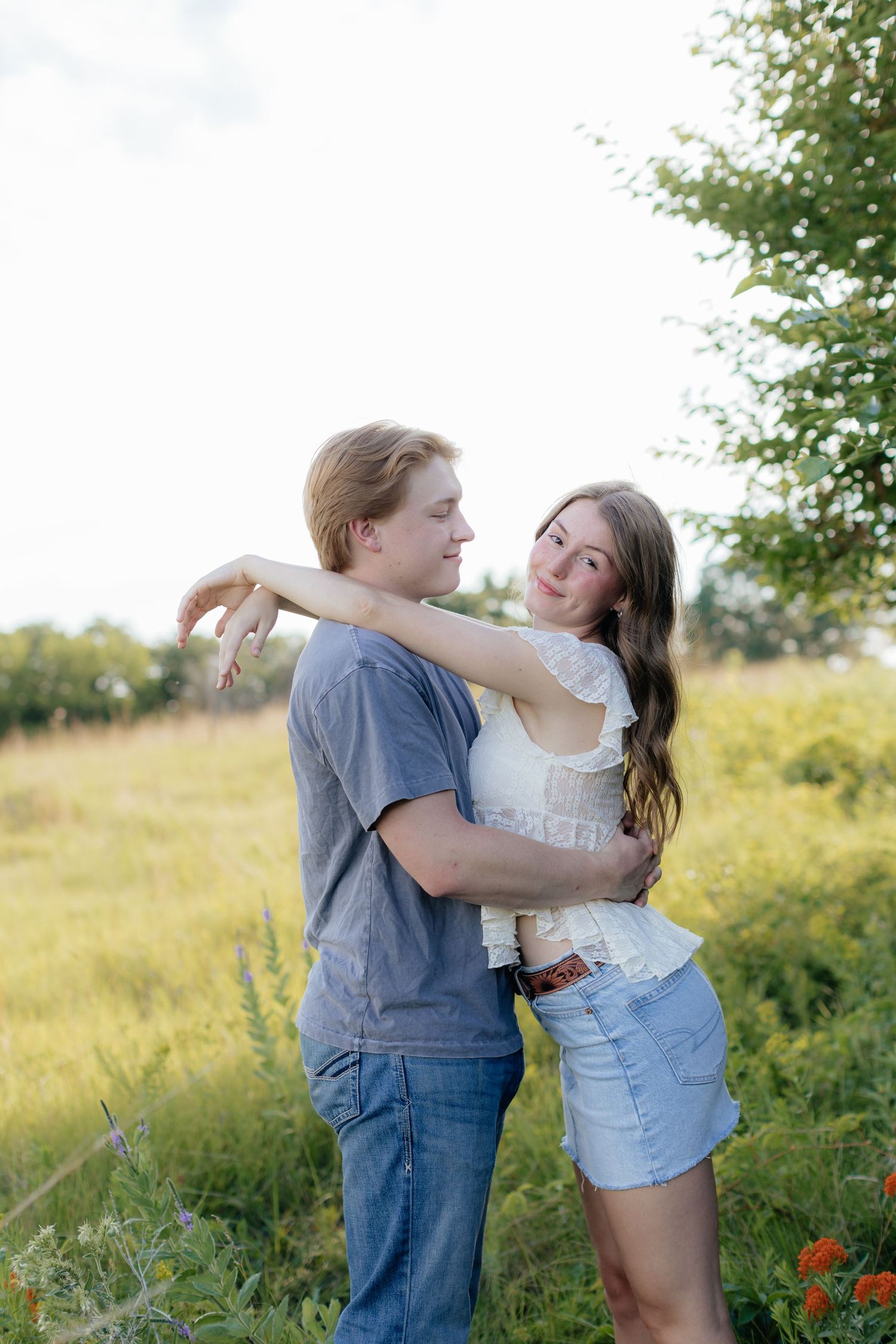 Romantic photo of a couple embracing on a hilltop at Prairie Bluffs, surrounded by open fields and wide Minnesota skies.