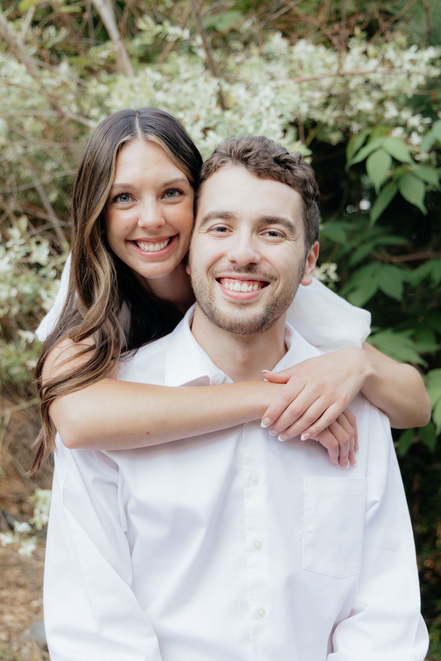 Golden-hour portrait of a couple embracing among tall trees at Pinewood in Cambridge, showcasing woodsy elegance.