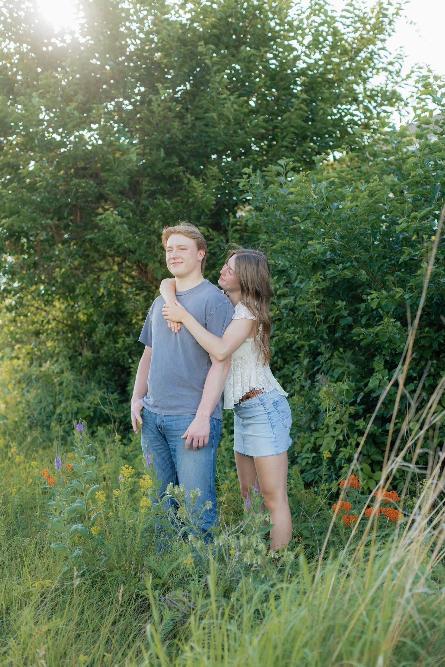 Romantic photo of a couple embracing on a hilltop at Prairie Bluffs, surrounded by open fields and wide Minnesota skies.