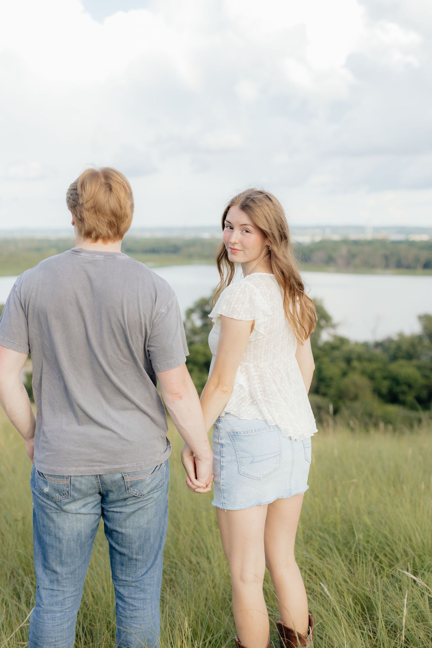 Romantic photo of a couple embracing on a hilltop at Prairie Bluffs, surrounded by open fields and wide Minnesota skies.