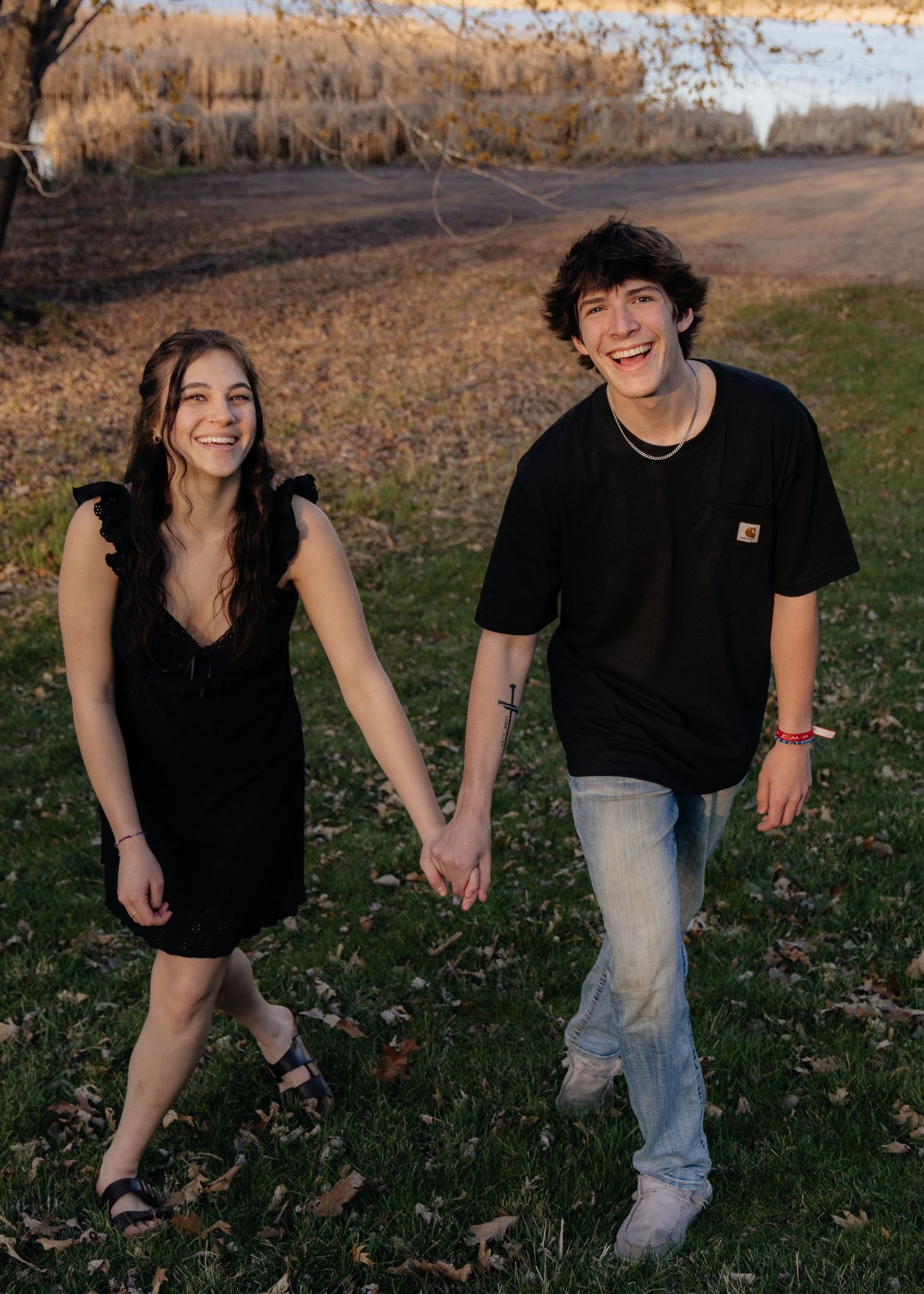 Couple laughing enjoying the blooming trees at Fish Lake Regional Park in Maple Grove, MN, with fresh green grass and soft spring sunlight