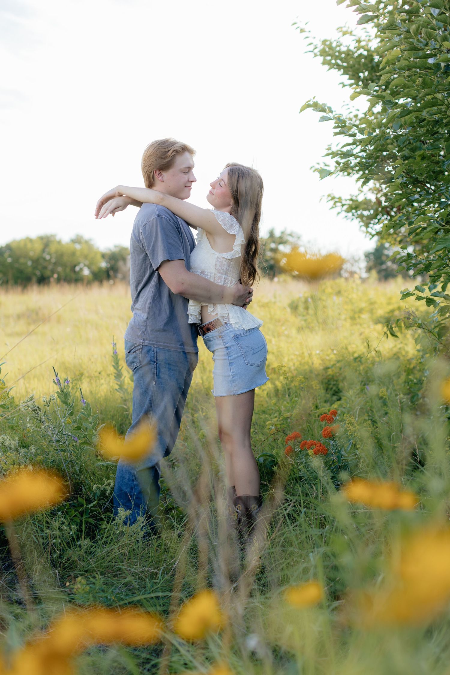 Romantic photo of a couple embracing on a hilltop at Prairie Bluffs, surrounded by open fields and wide Minnesota skies.