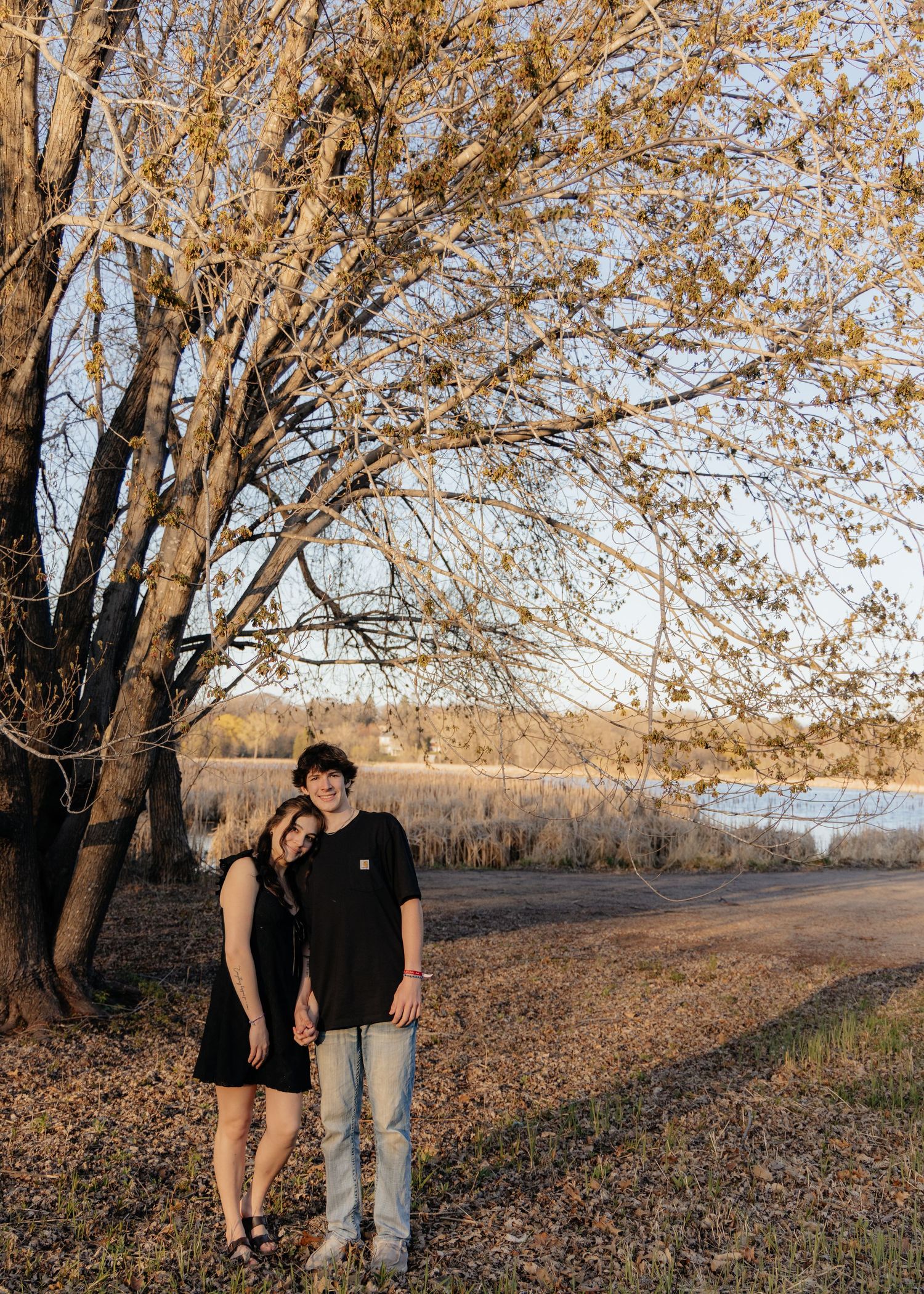 Couple laughing enjoying the blooming trees at Fish Lake Regional Park in Maple Grove, MN, with fresh green grass and soft spring sunlight