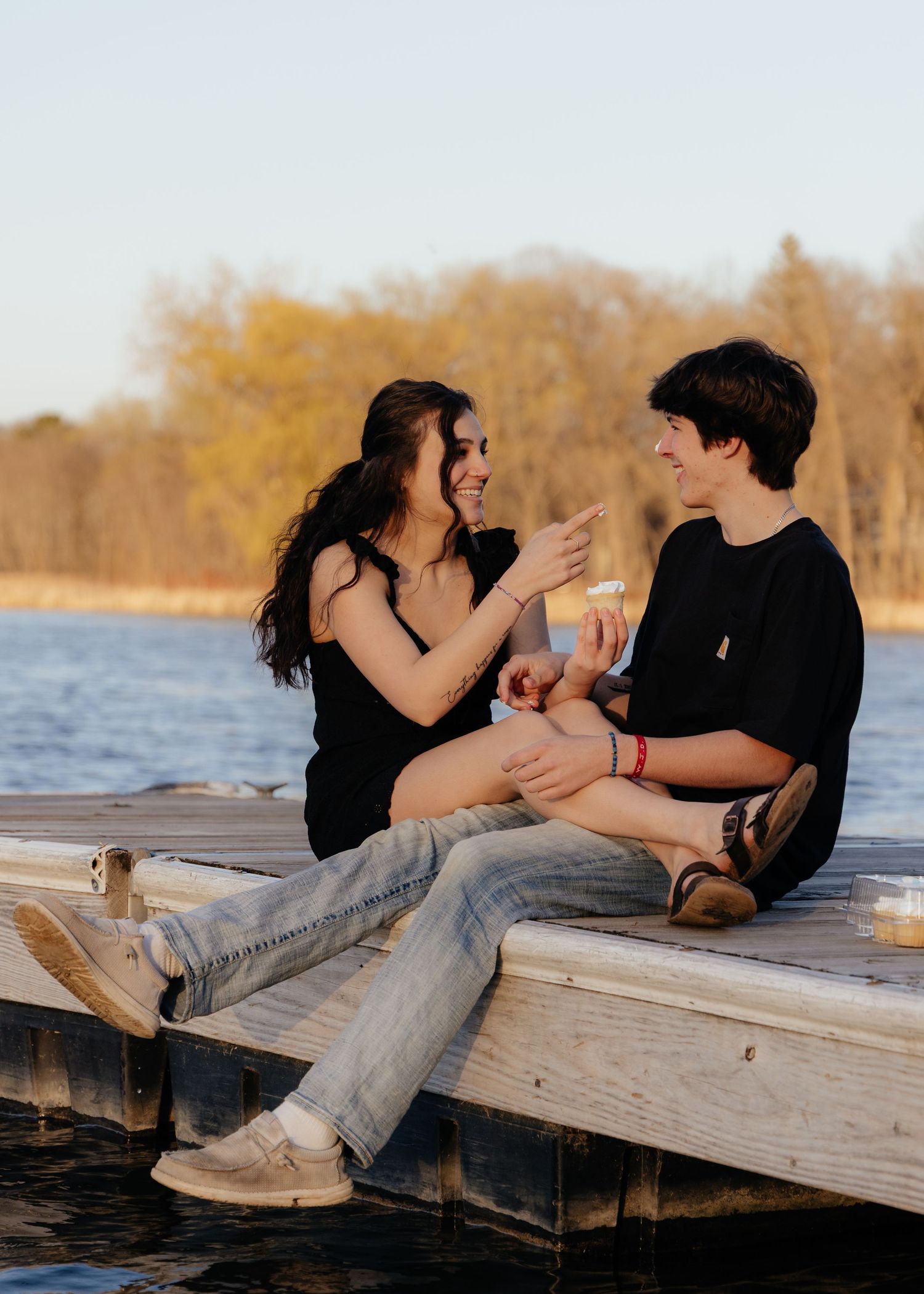 Couple laughing enjoying the blooming trees at Fish Lake Regional Park in Maple Grove, MN, with fresh green grass and soft spring sunlight