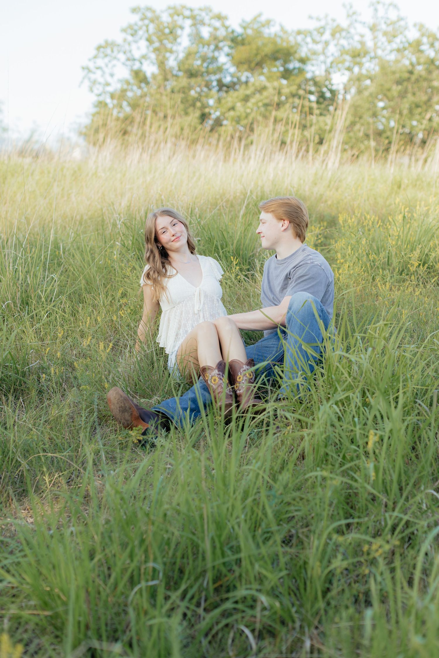 Romantic photo of a couple embracing on a hilltop at Prairie Bluffs, surrounded by open fields and wide Minnesota skies.