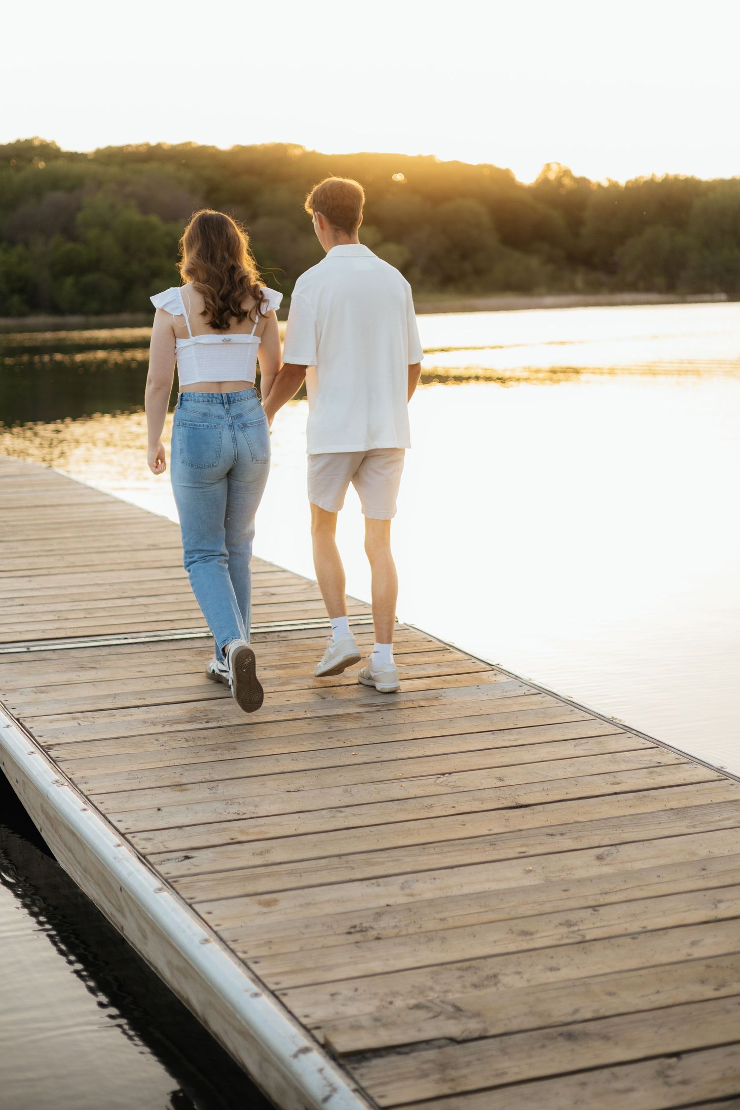 Couple smiling together along the lakeshore at Fish Lake Regional Park in Maple Grove, MN, with bright green trees and clear blue water