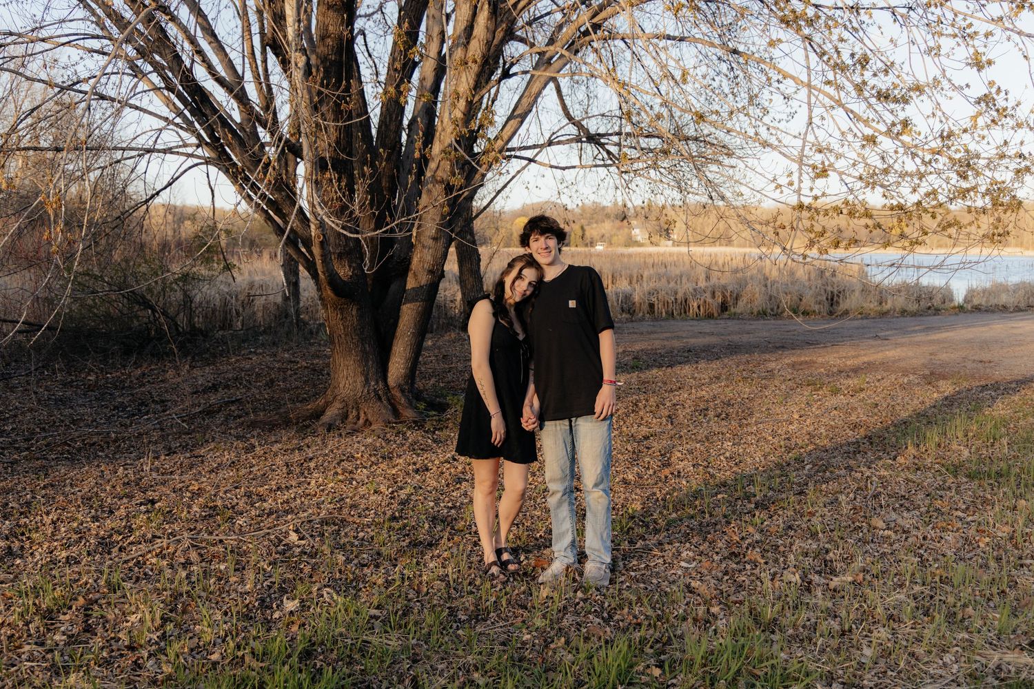 Couple laughing enjoying the blooming trees at Fish Lake Regional Park in Maple Grove, MN, with fresh green grass and soft spring sunlight