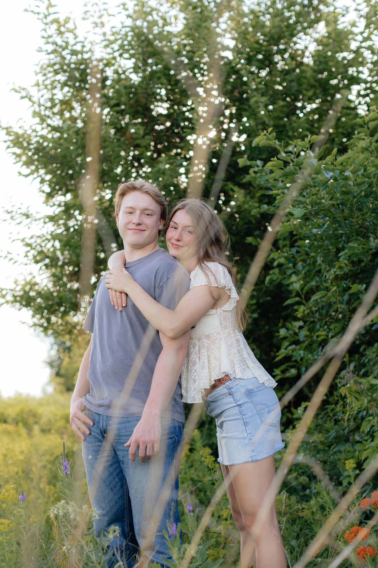 Romantic photo of a couple embracing on a hilltop at Prairie Bluffs, surrounded by open fields and wide Minnesota skies.