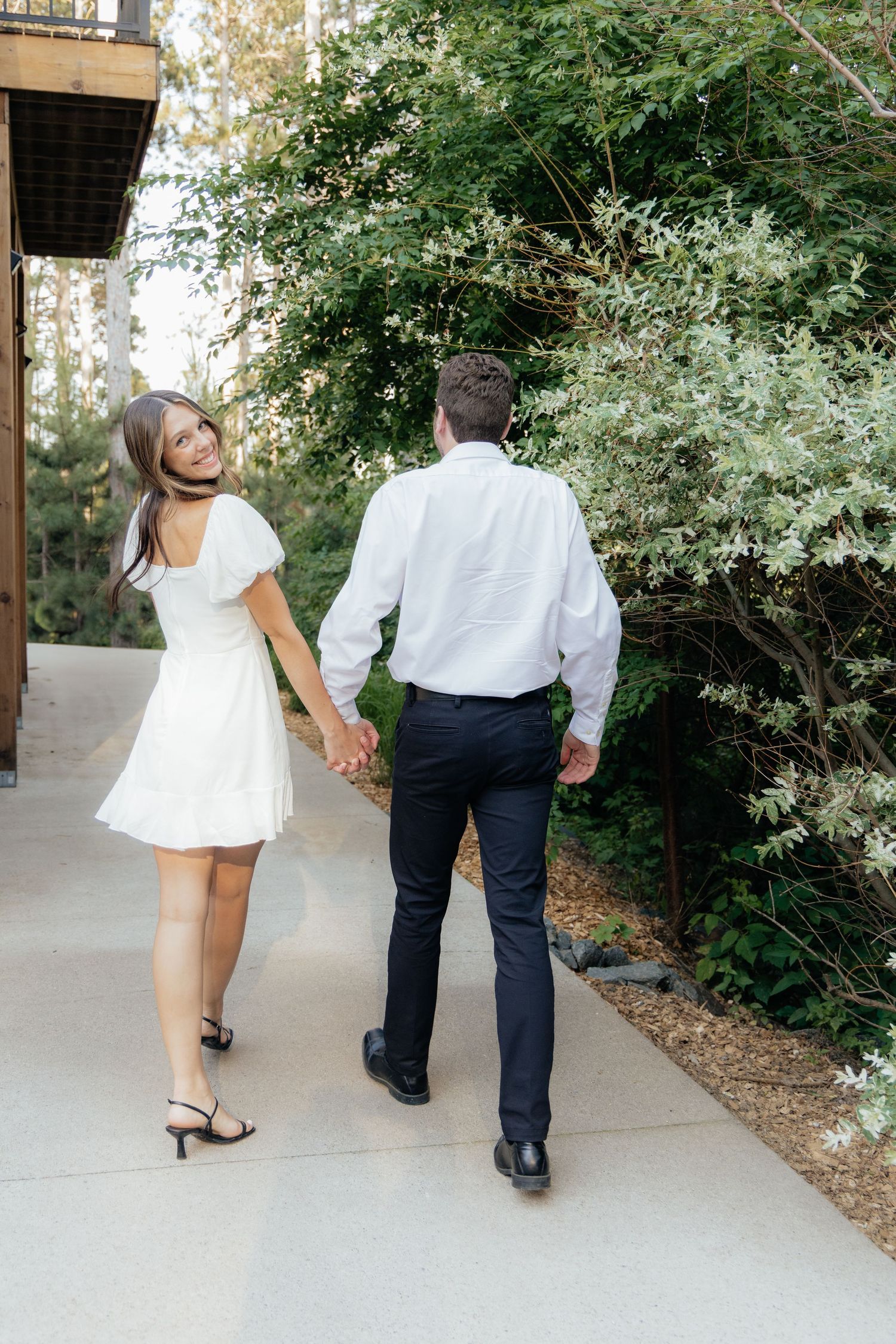 Golden-hour portrait of a couple embracing among tall trees at Pinewood in Cambridge, showcasing woodsy elegance.