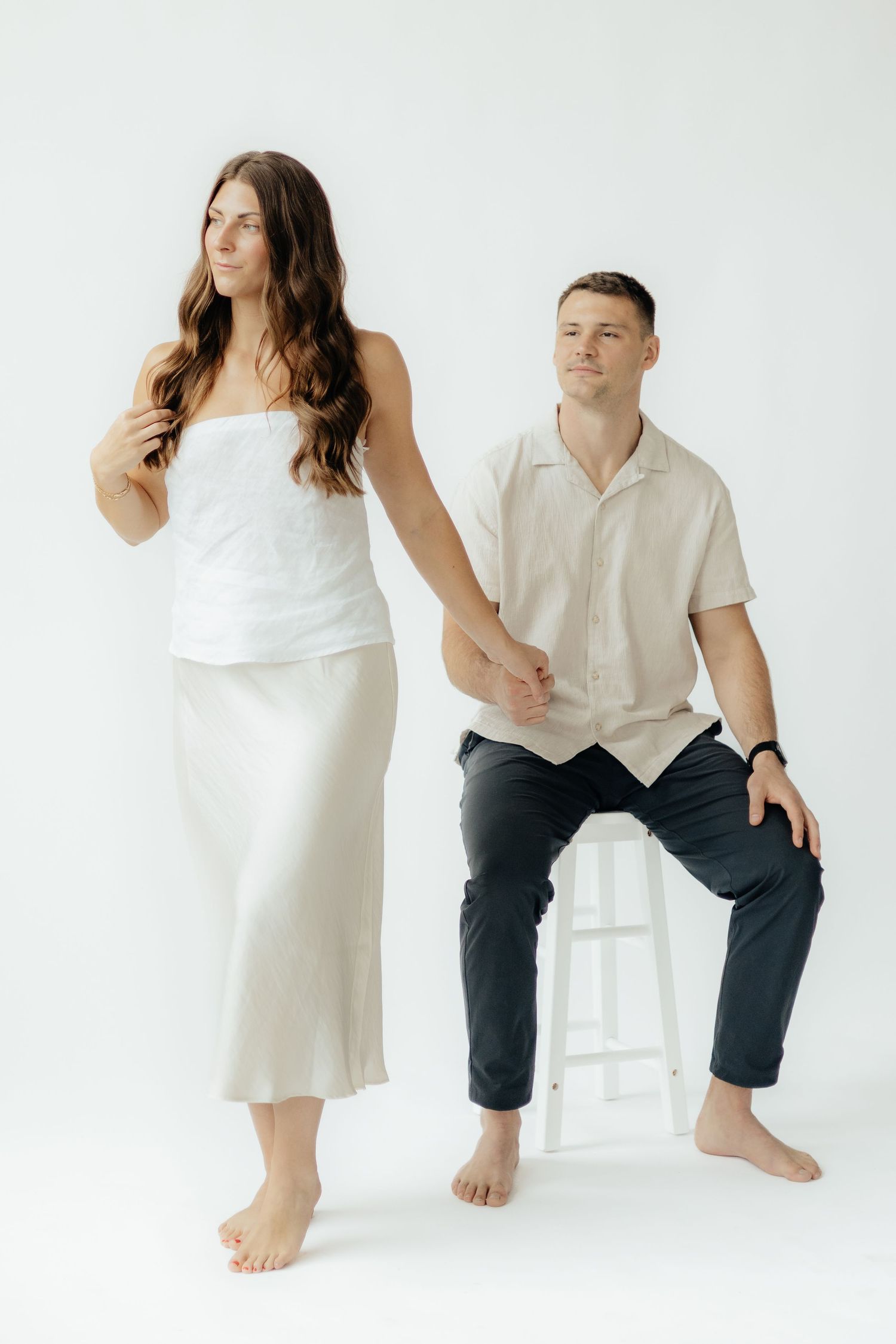 Couple embracing in soft natural light at Abide Studio in Minneapolis, MN, with minimalist white walls and warm, cozy tones
