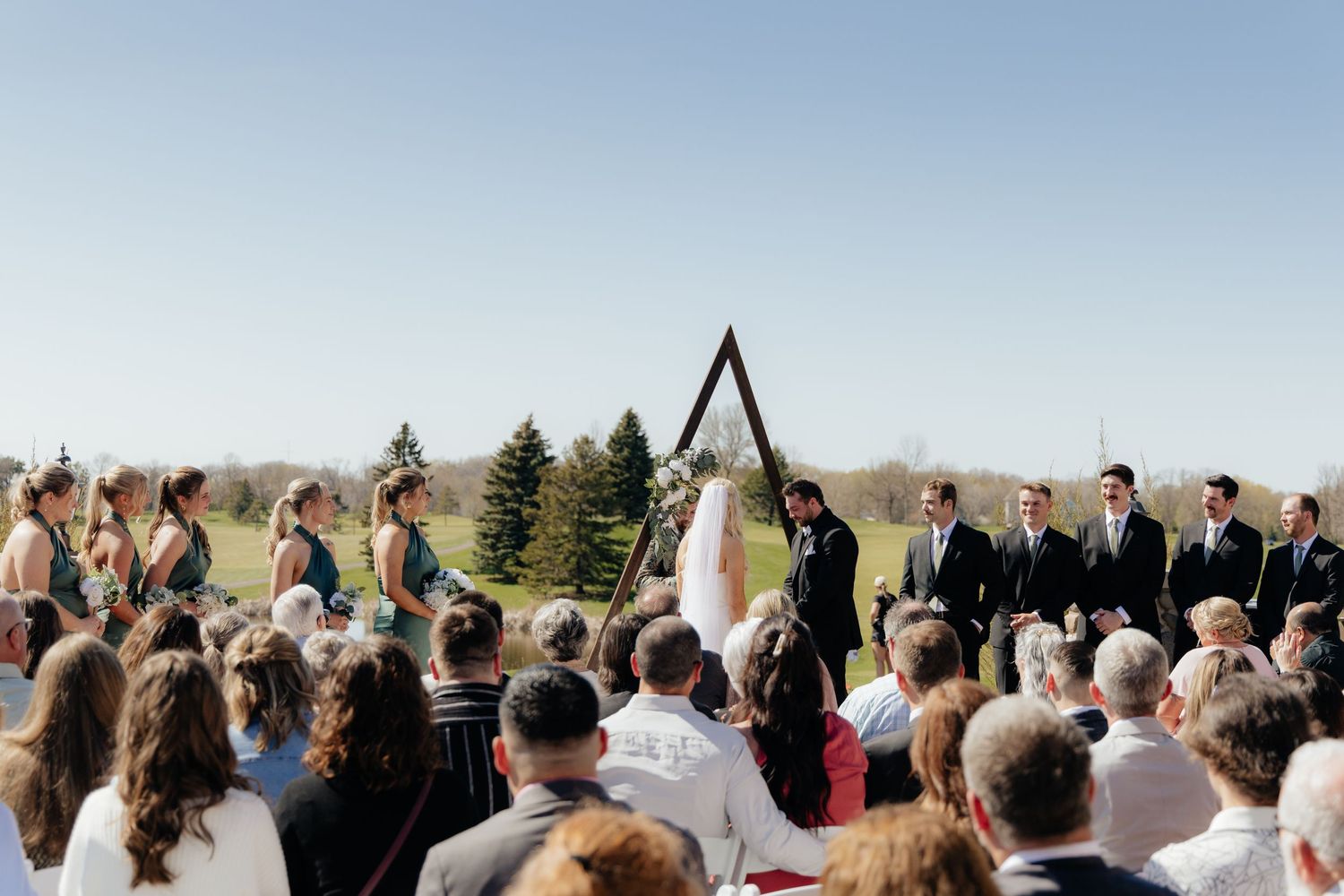 Bride and groom sharing a romantic moment at Rush Creek Golf Course in Maple Grove, MN, with rolling fairways and elegant floral decor