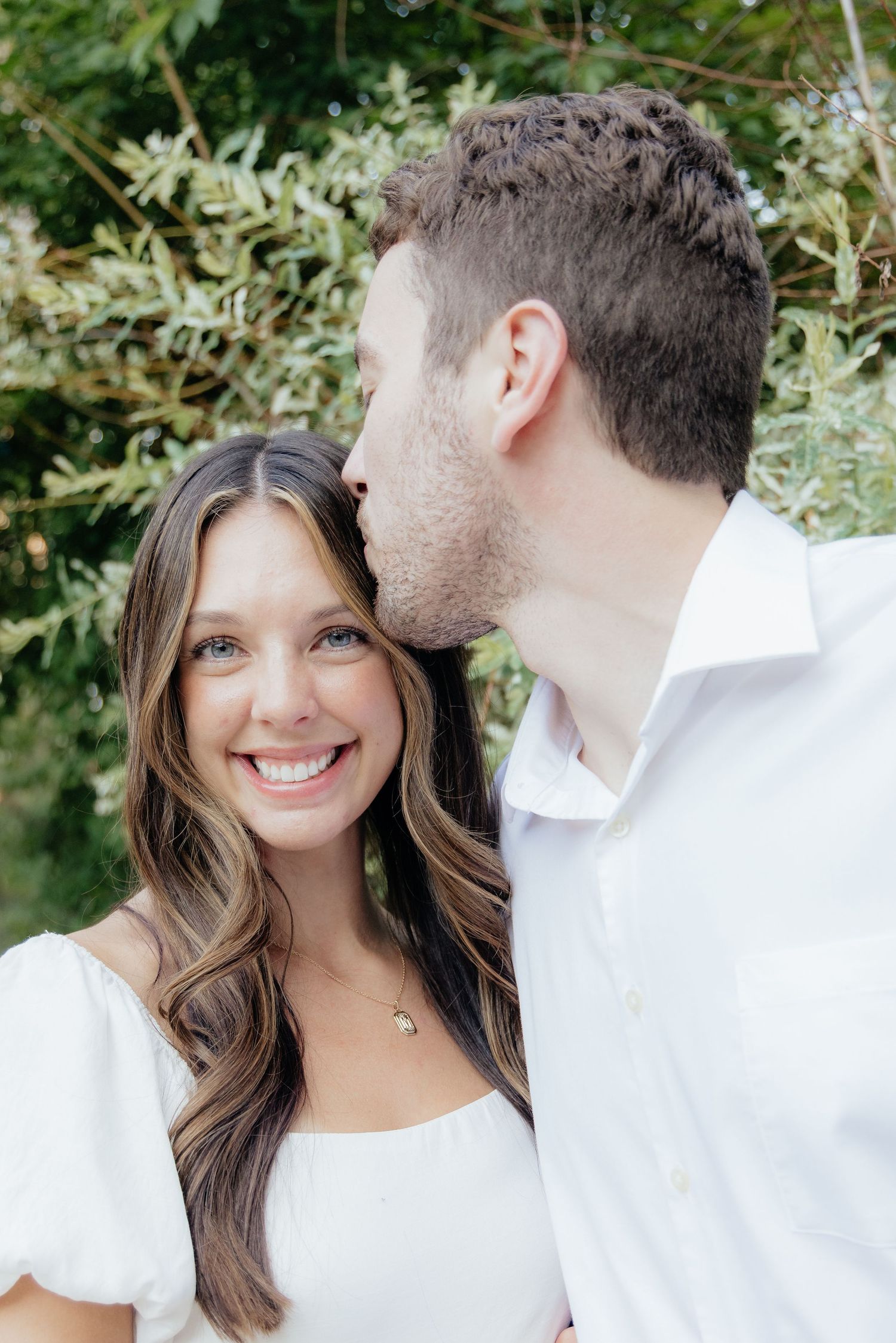 Golden-hour portrait of a couple embracing among tall trees at Pinewood in Cambridge, showcasing woodsy elegance.