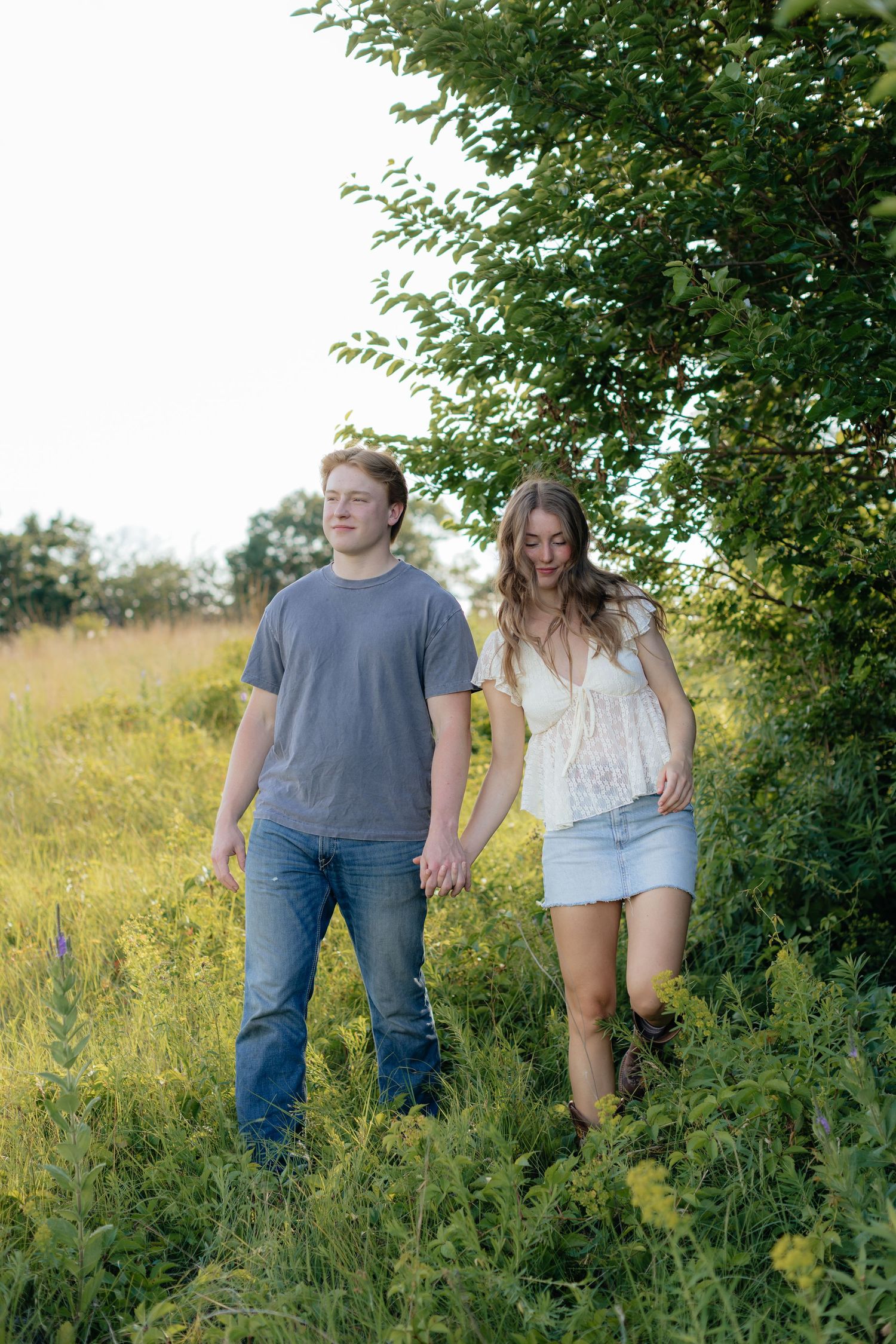 Romantic photo of a couple embracing on a hilltop at Prairie Bluffs, surrounded by open fields and wide Minnesota skies.