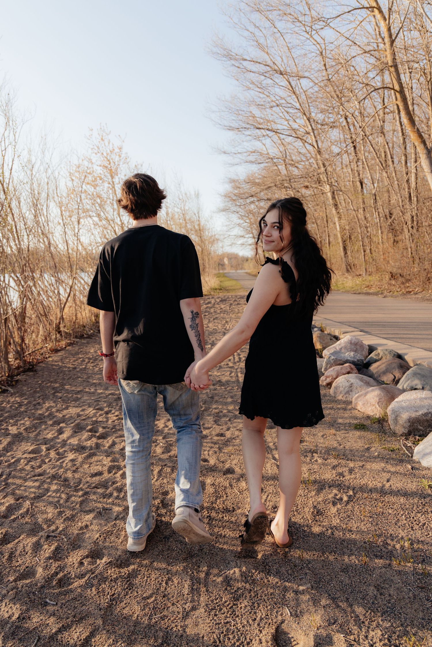 Couple laughing enjoying the blooming trees at Fish Lake Regional Park in Maple Grove, MN, with fresh green grass and soft spring sunlight