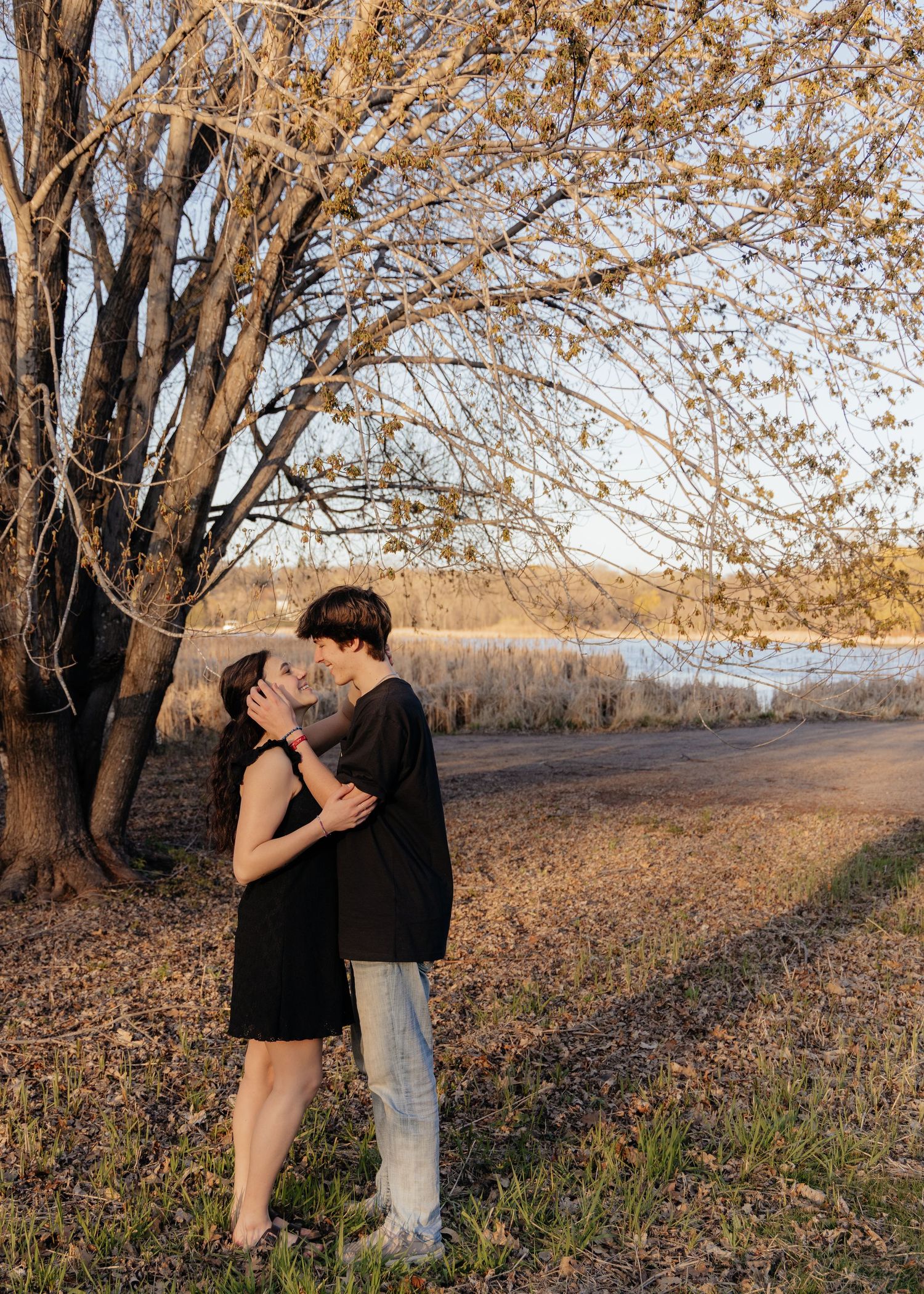 Couple laughing enjoying the blooming trees at Fish Lake Regional Park in Maple Grove, MN, with fresh green grass and soft spring sunlight