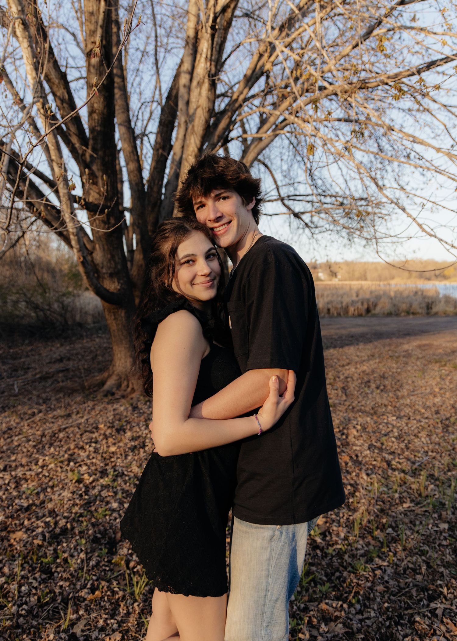 Couple laughing enjoying the blooming trees at Fish Lake Regional Park in Maple Grove, MN, with fresh green grass and soft spring sunlight