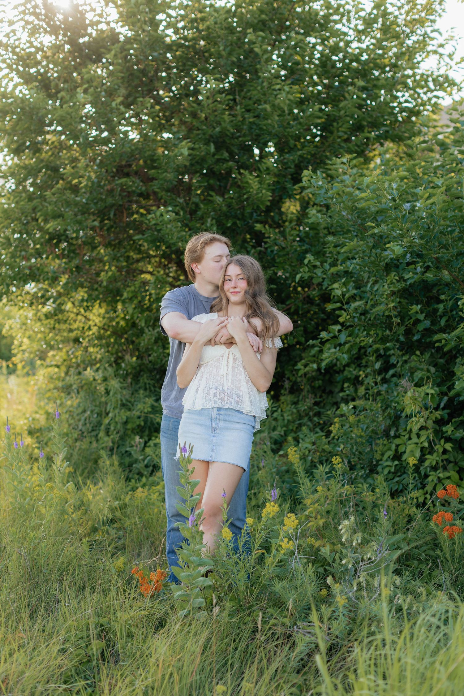 Romantic photo of a couple embracing on a hilltop at Prairie Bluffs, surrounded by open fields and wide Minnesota skies.