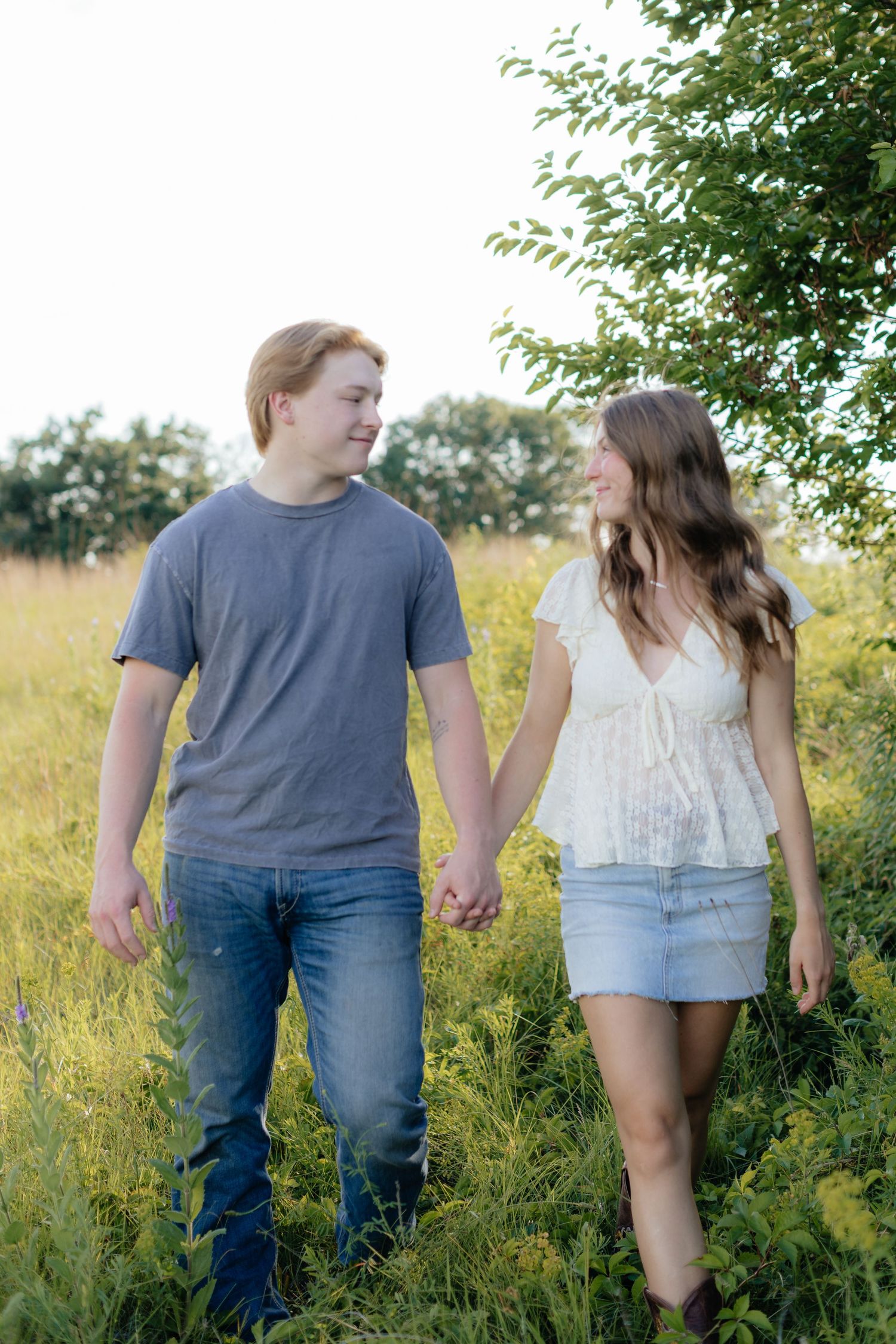 Romantic photo of a couple embracing on a hilltop at Prairie Bluffs, surrounded by open fields and wide Minnesota skies.