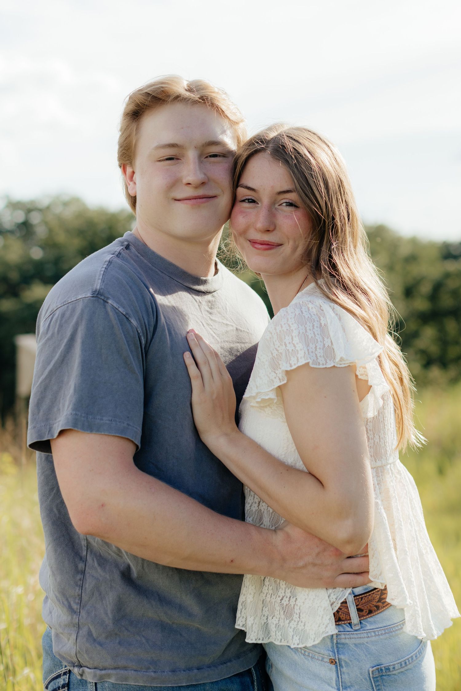 Romantic photo of a couple embracing on a hilltop at Prairie Bluffs, surrounded by open fields and wide Minnesota skies.