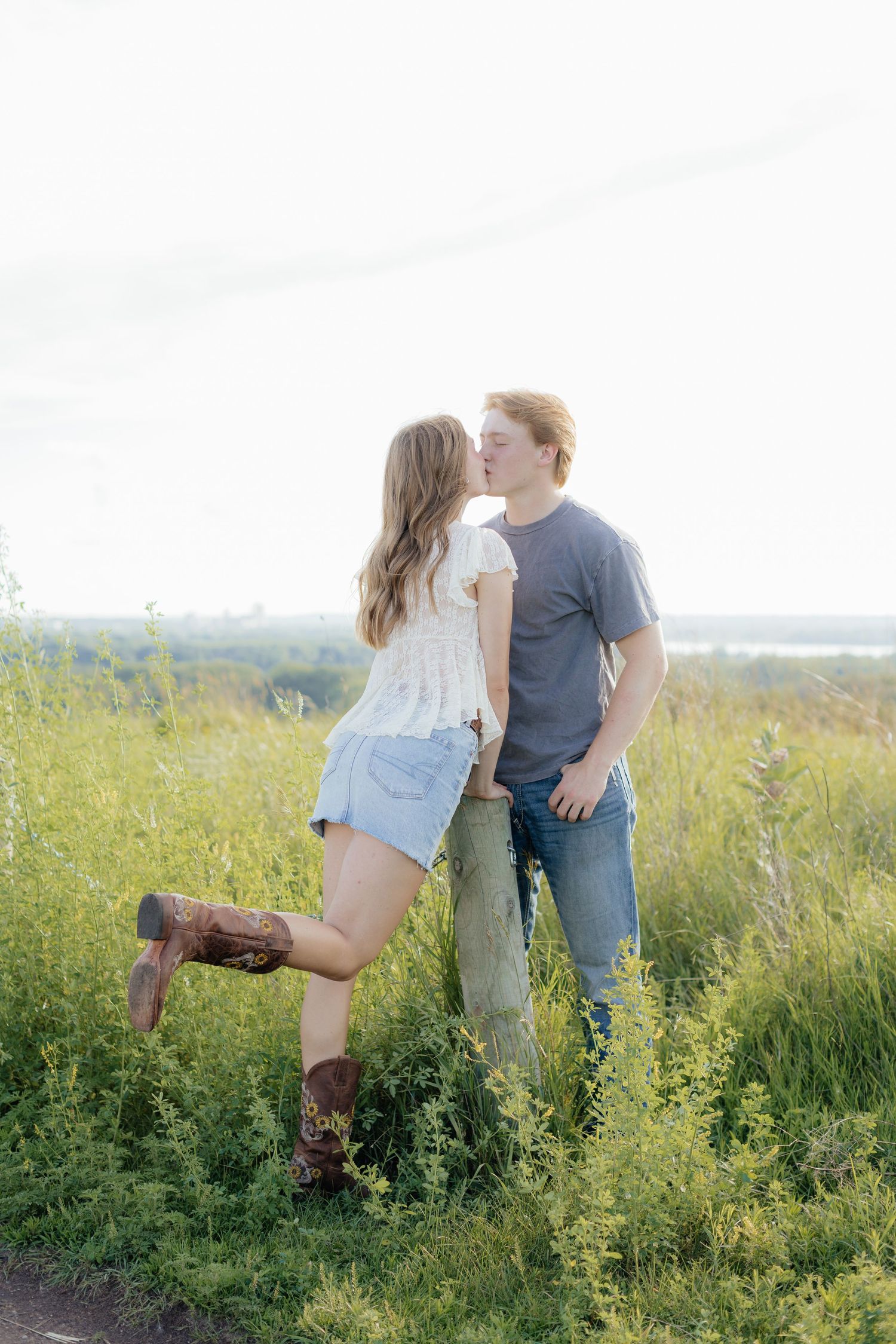 Romantic photo of a couple embracing on a hilltop at Prairie Bluffs, surrounded by open fields and wide Minnesota skies.
