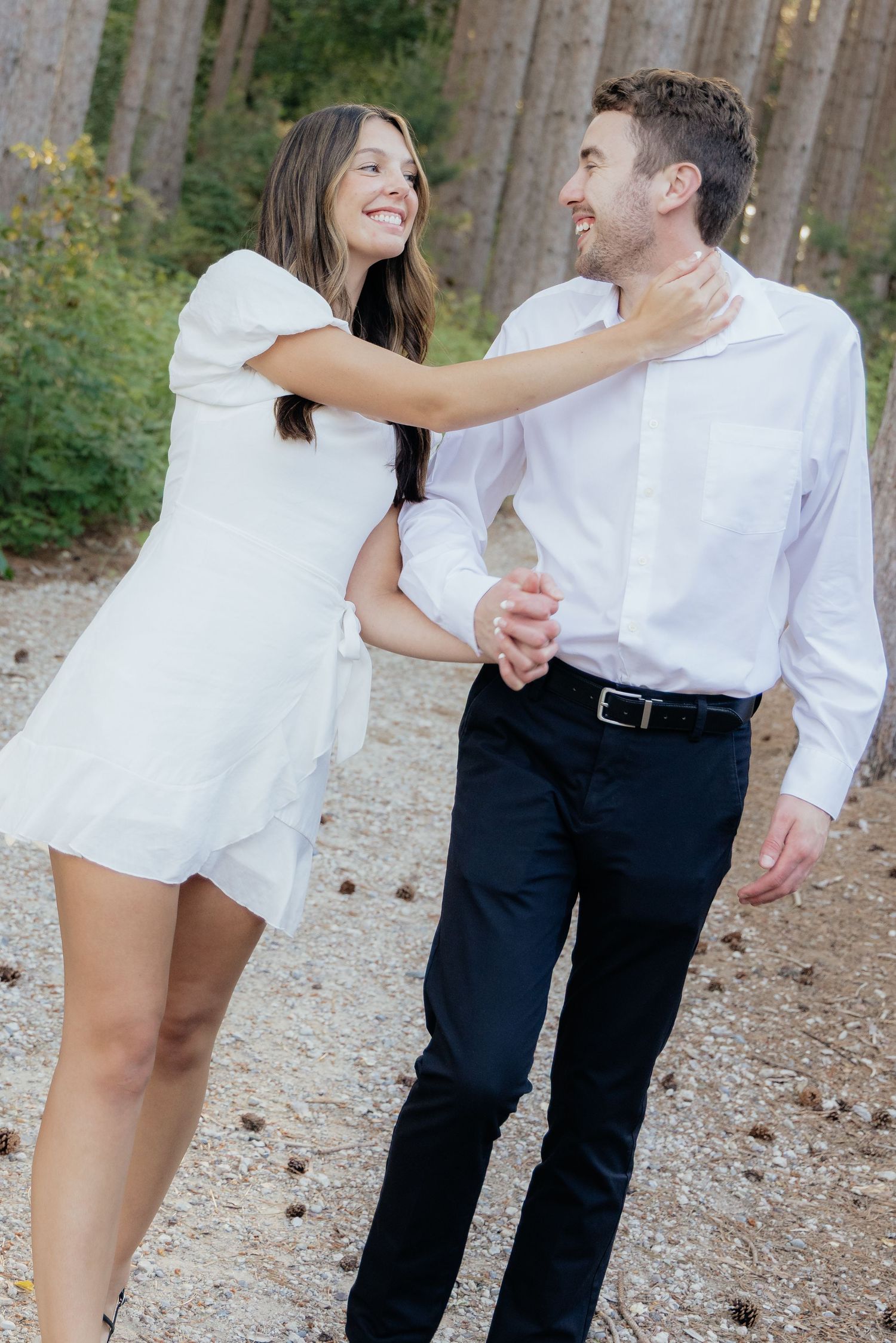 Golden-hour portrait of a couple embracing among tall trees at Pinewood in Cambridge, showcasing woodsy elegance.