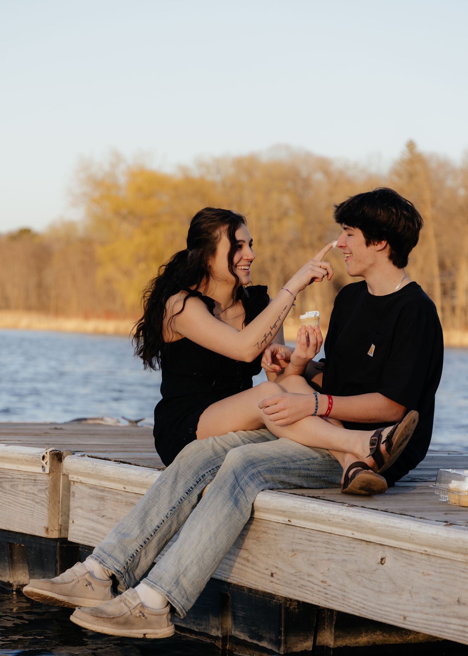 Couple laughing enjoying the blooming trees at Fish Lake Regional Park in Maple Grove, MN, with fresh green grass and soft spring sunlight