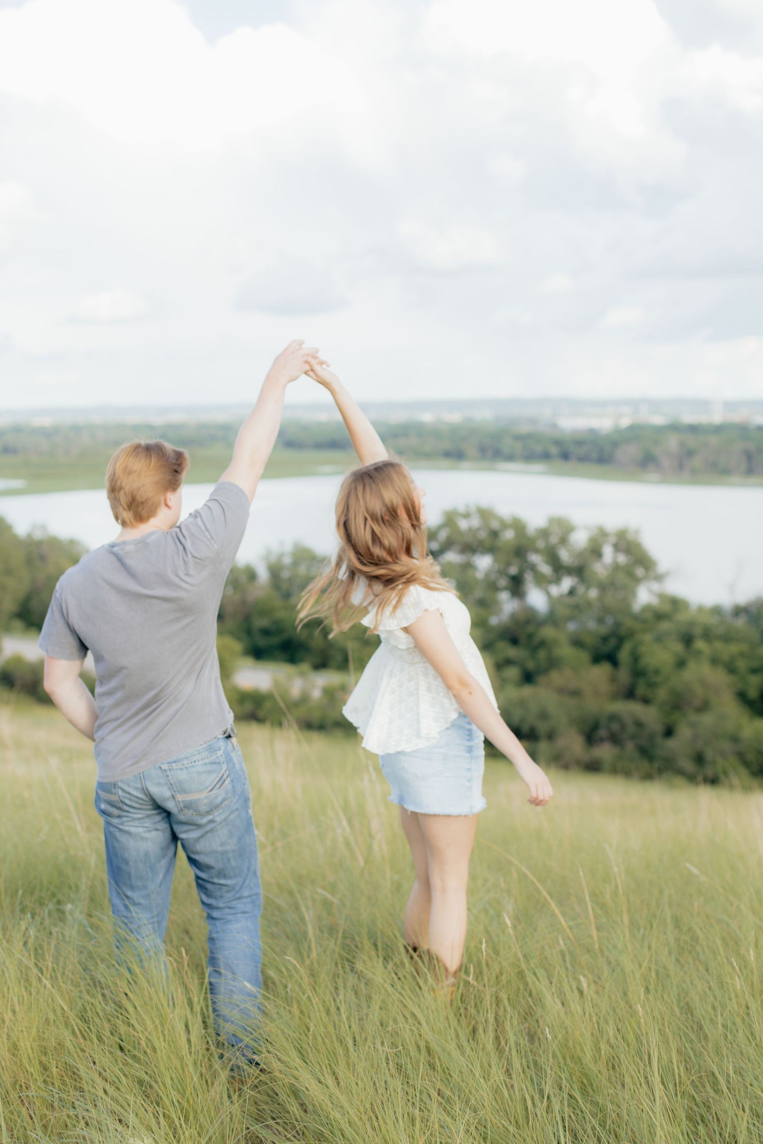 Romantic photo of a couple embracing on a hilltop at Prairie Bluffs, surrounded by open fields and wide Minnesota skies.