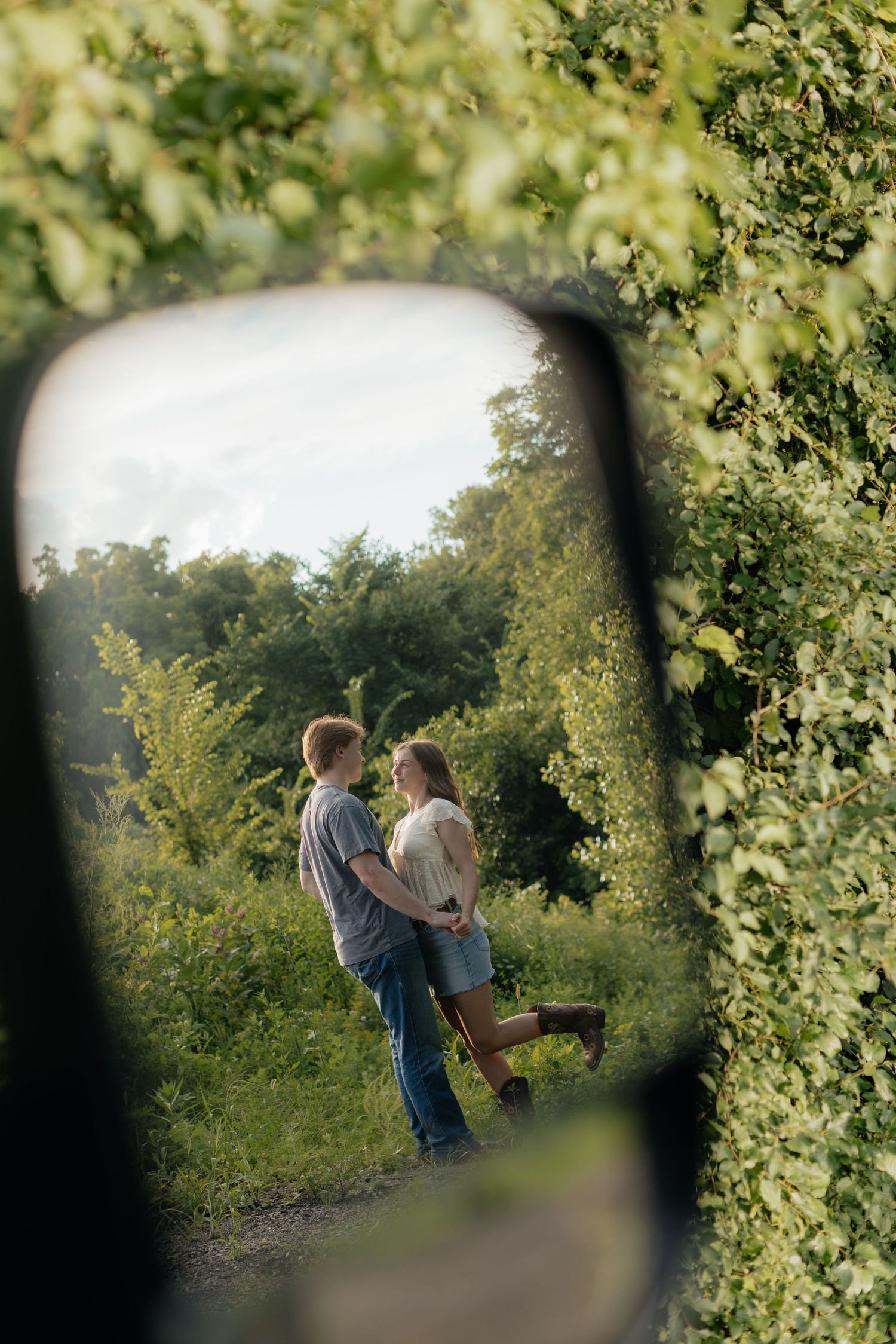 Romantic photo of a couple embracing on a hilltop at Prairie Bluffs, surrounded by open fields and wide Minnesota skies.