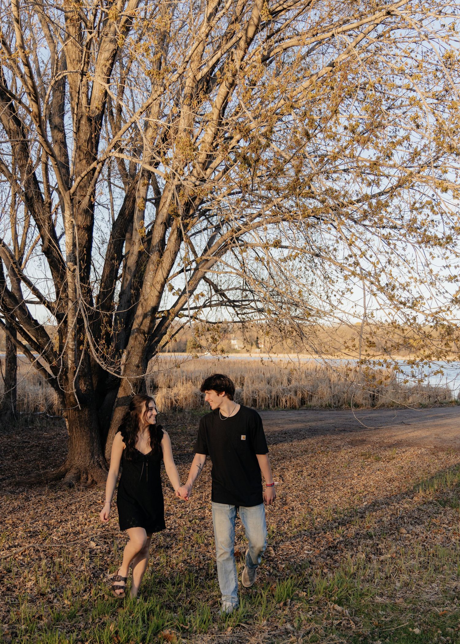 Couple laughing enjoying the blooming trees at Fish Lake Regional Park in Maple Grove, MN, with fresh green grass and soft spring sunlight