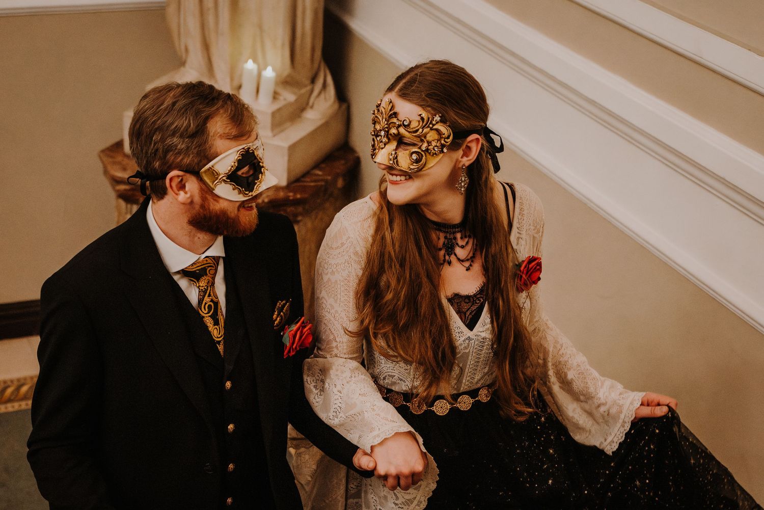 Partygoers in formal wear and decorative masks pose together at an elegant fantasy ball.