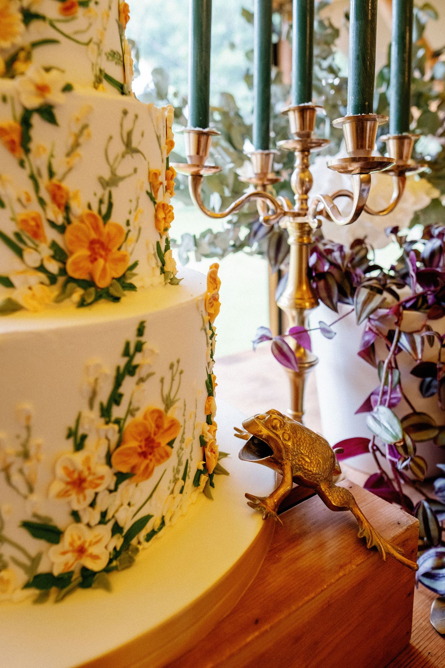 Wedding decor detail showing gold candelabra and floral arrangements on wooden surface.