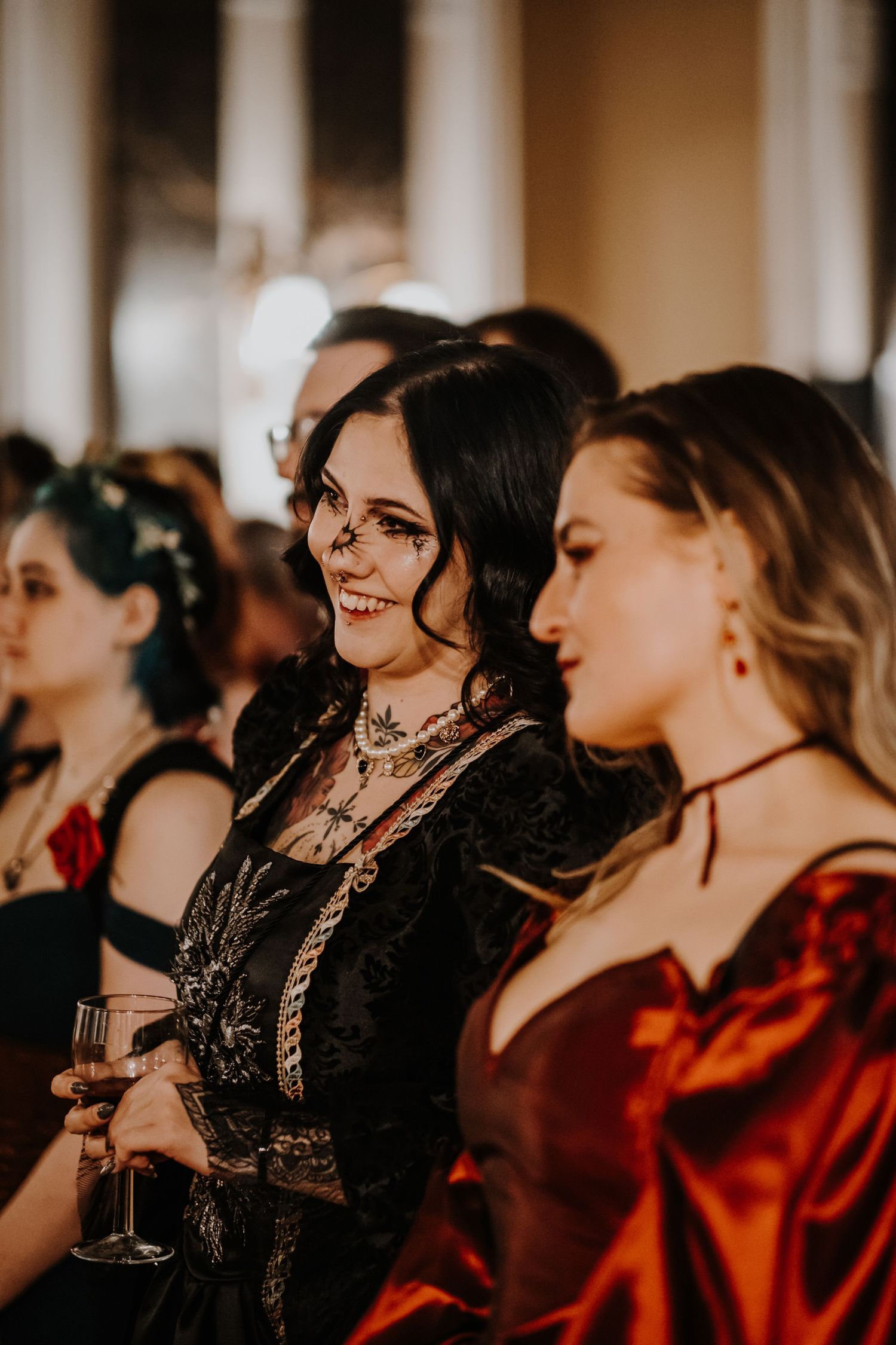 Group wearing elegant gothic masquerade attire in black and red at formal gathering.