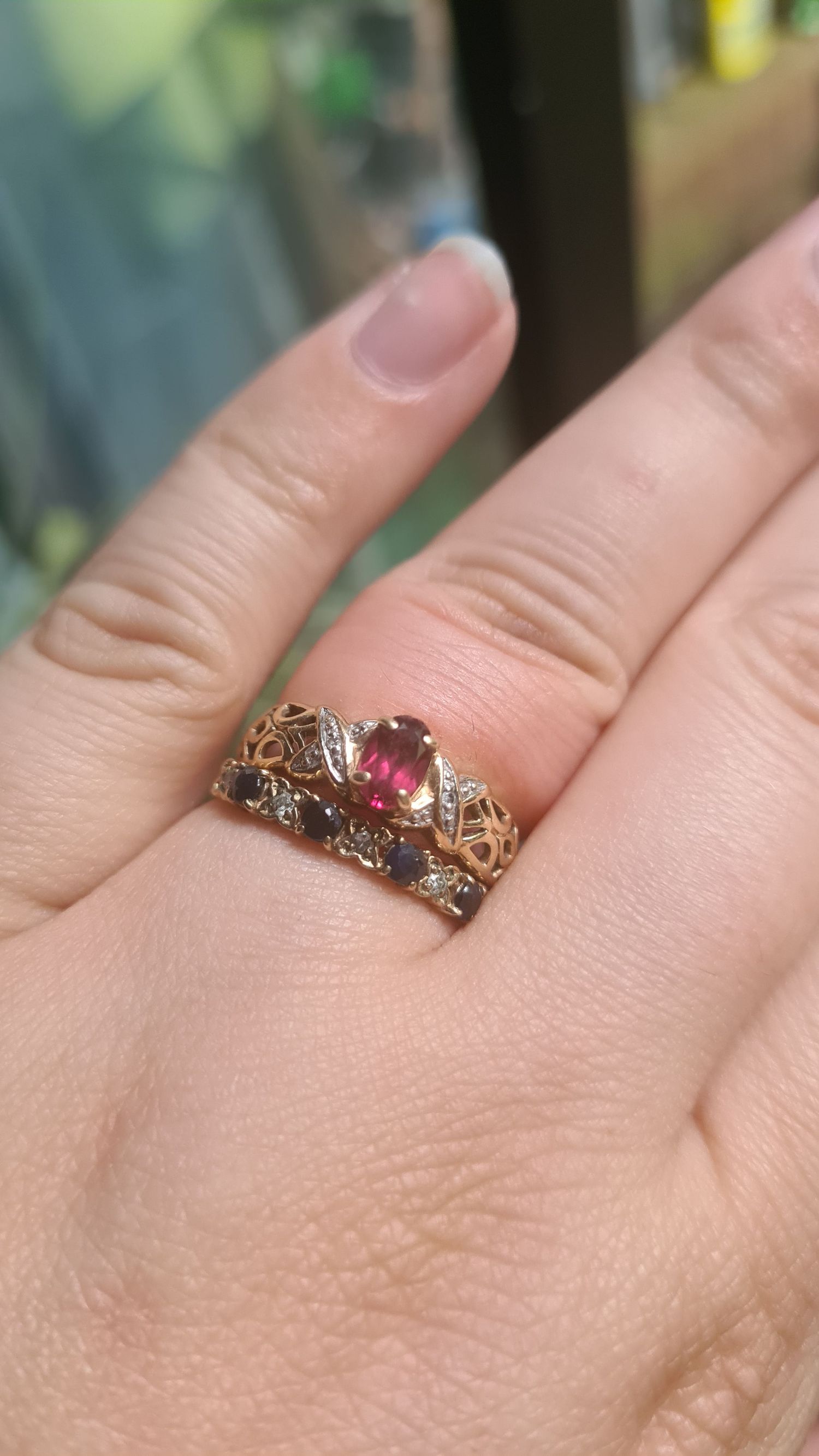 Close-up of an ornate vintage-style ring with pink gemstone on someone's hand.