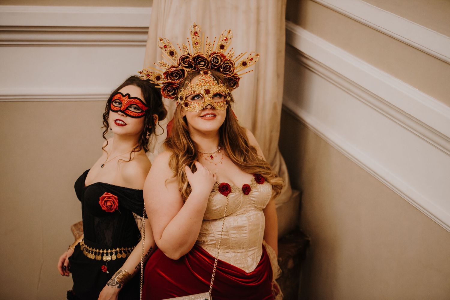 People in elegant masquerade attire and ornate masks gather for group photos at a fantasy ball.