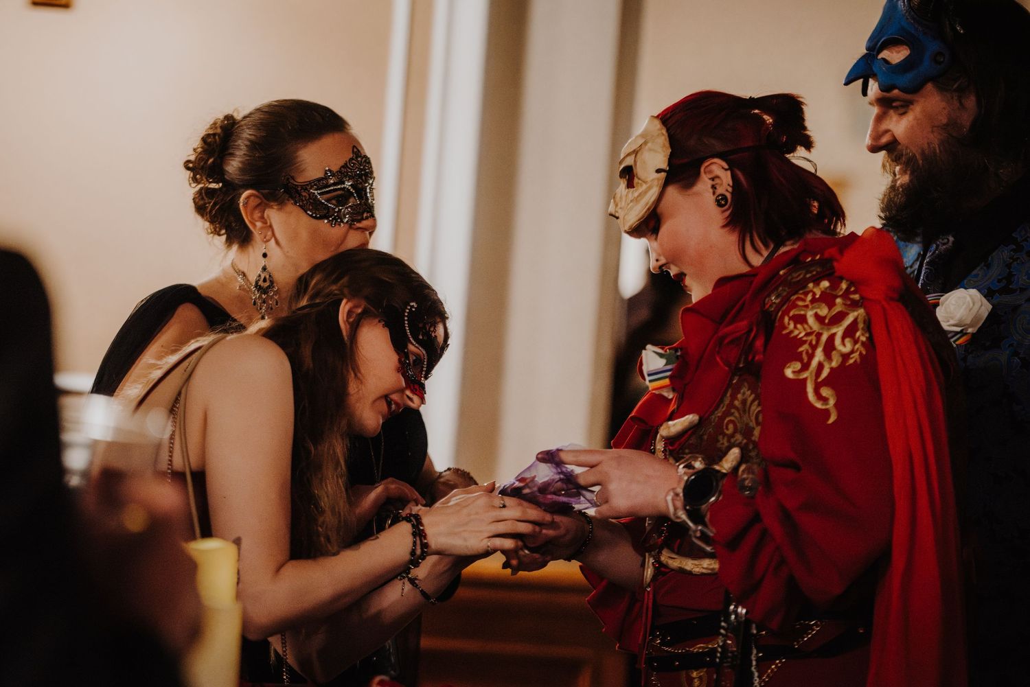 Guests in elegant masquerade attire dance and celebrate at an indoor fantasy ball.