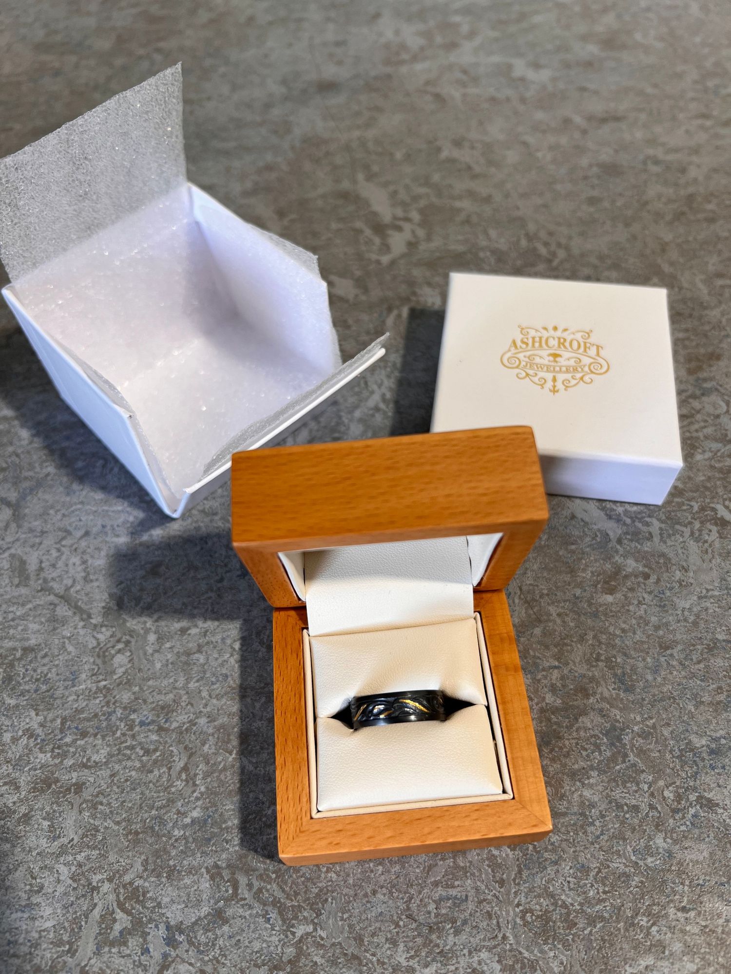 Wooden ring box opening sequence showing a black wedding band inside.