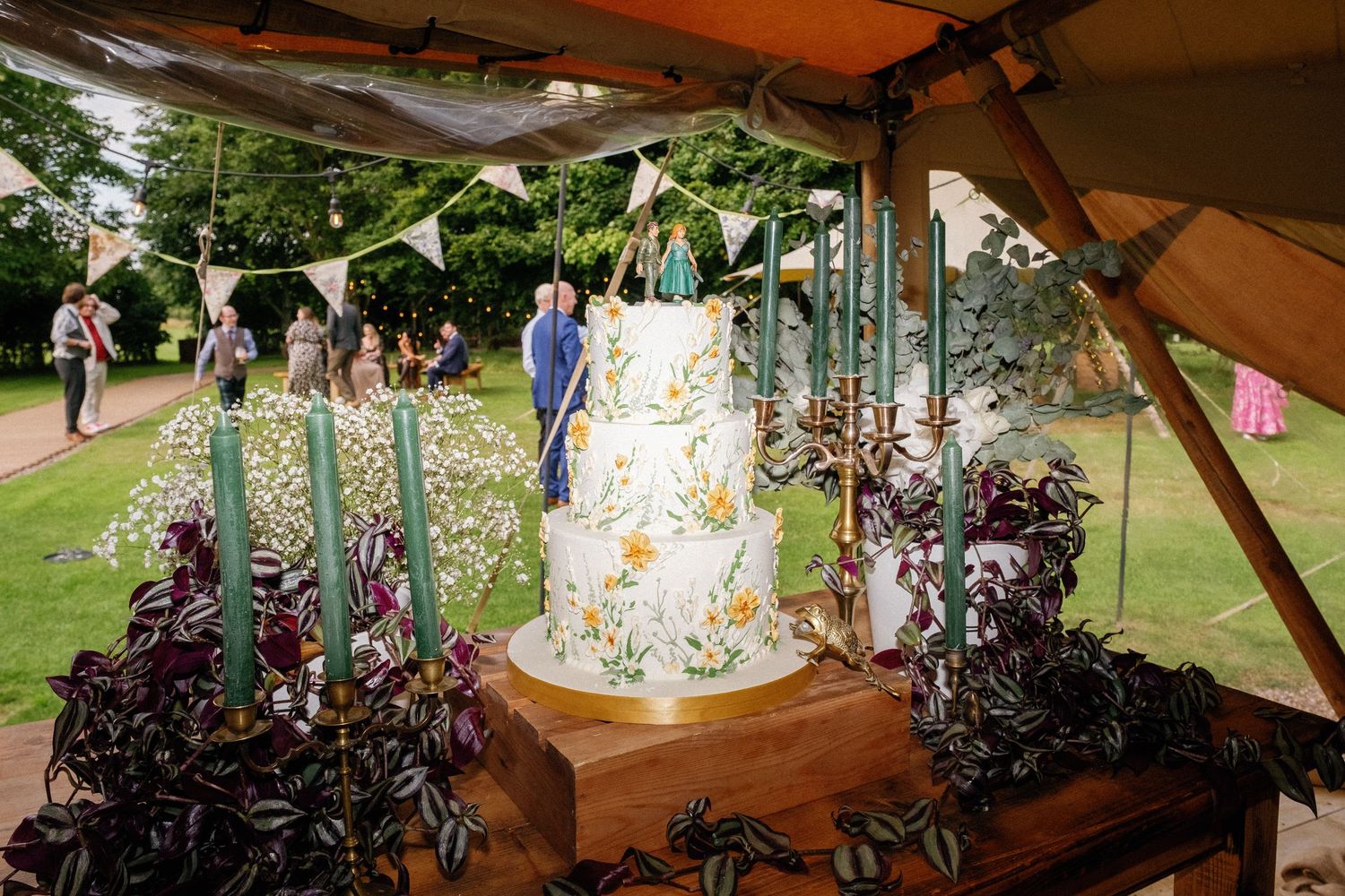 Wedding reception tent decorated with hanging lights and floral bunting.