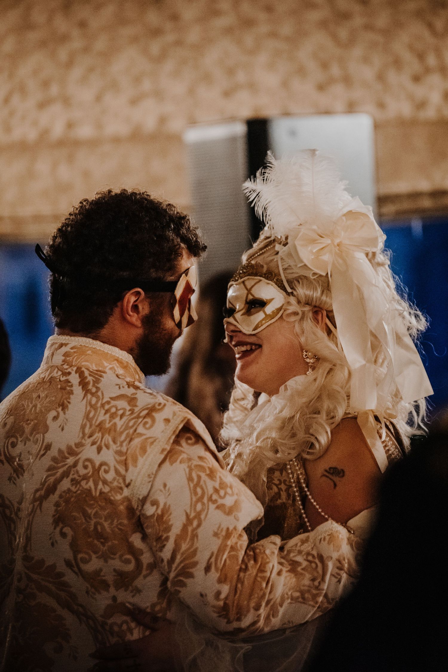 Couple in white lace and feathers dancing at masquerade ball.