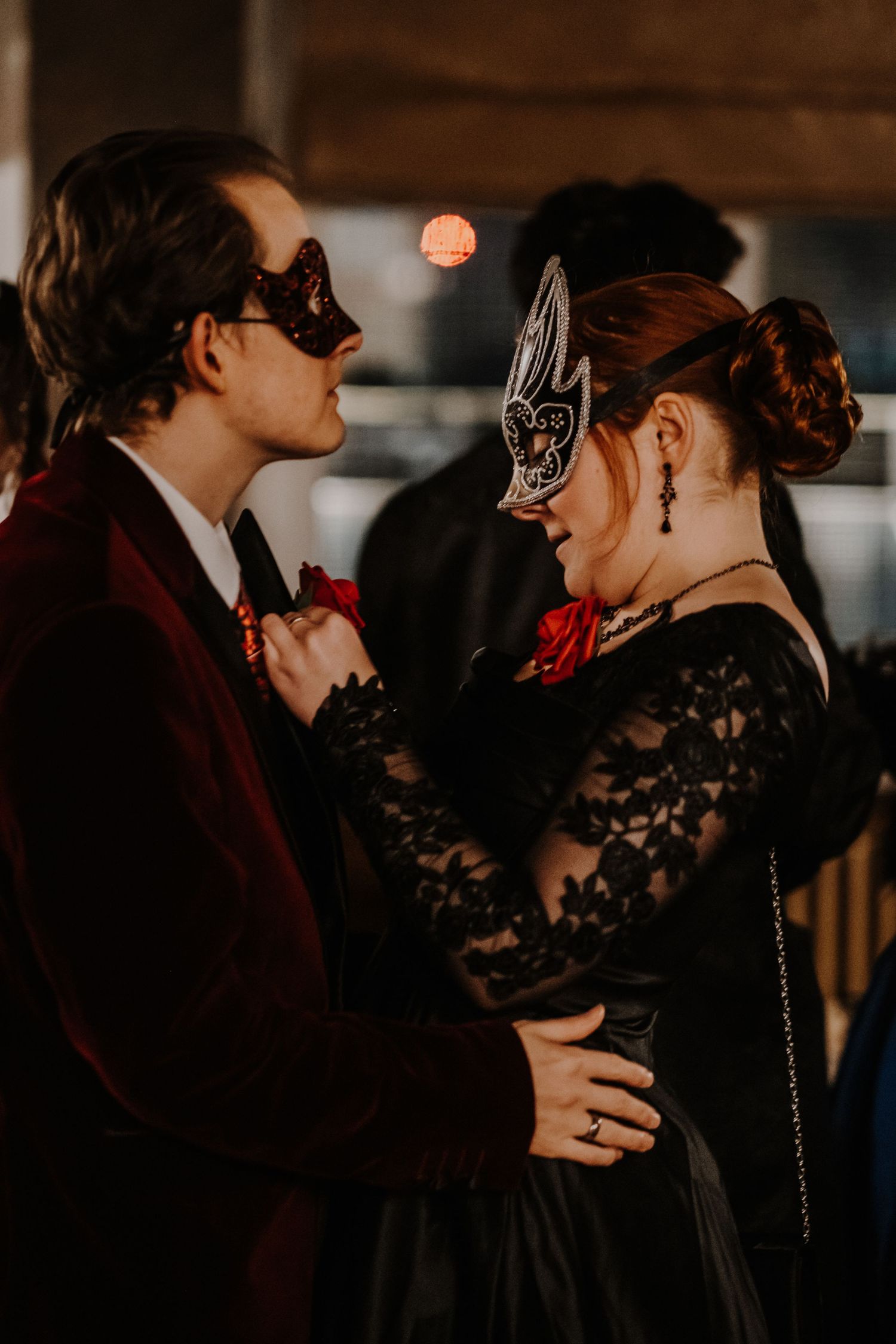 Couple in formal attire dancing at a masquerade ball with ornate masks and vintage-inspired clothing.