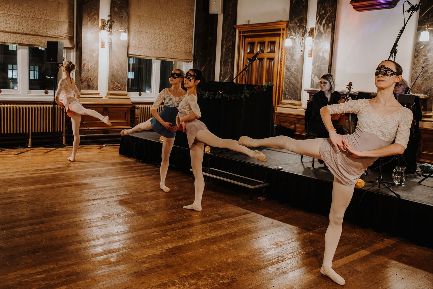 Ballet dancers perform their positions and movements on a wooden floor in a fantasy ball.