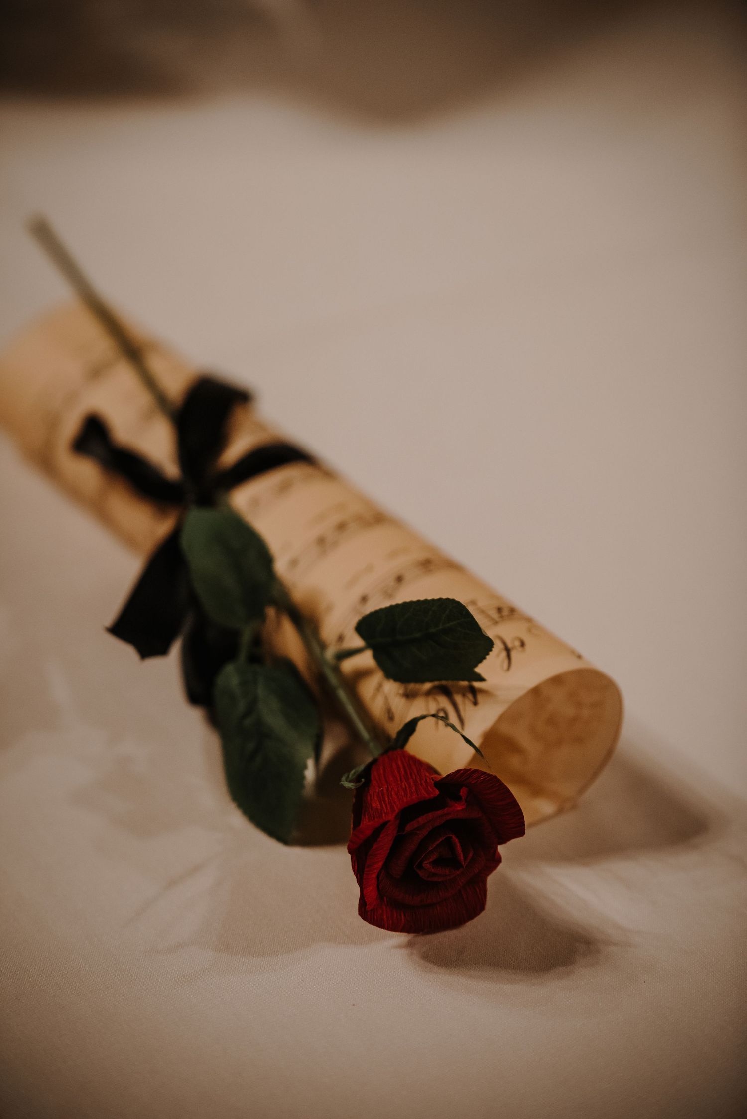 Single red rose laying on vintage sheet music in moody lighting.